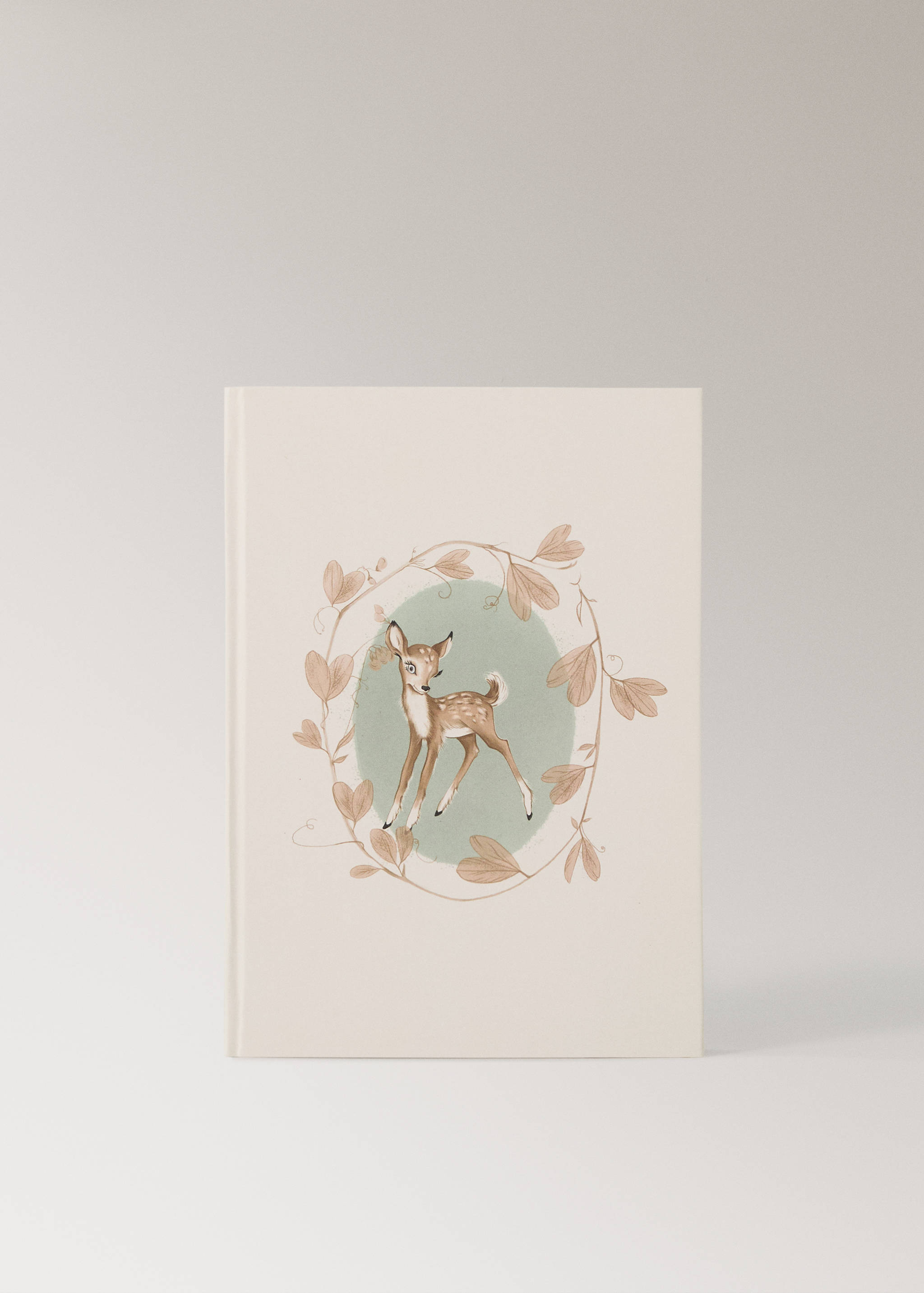 Libreta de color crema con ilustración de ciervo rodeado de hojas.