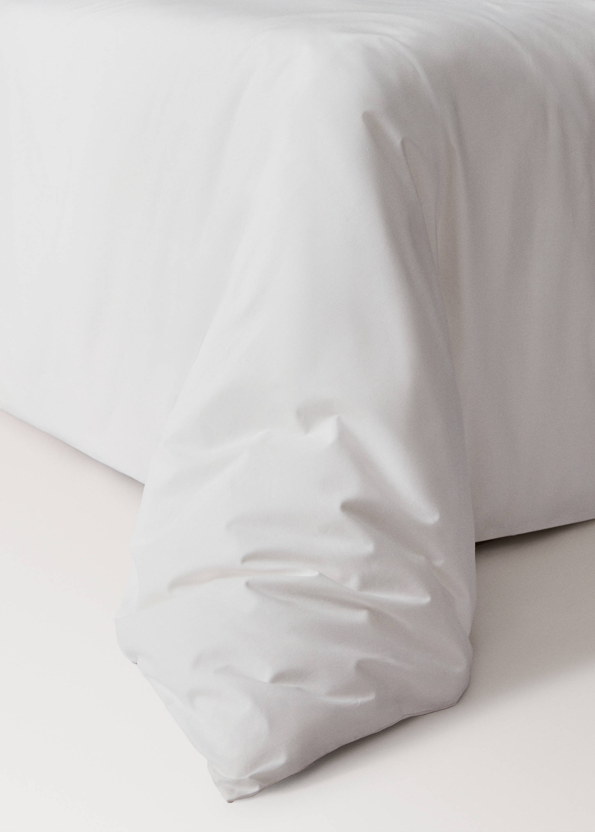 Plain white duvet cover draped over a bed.