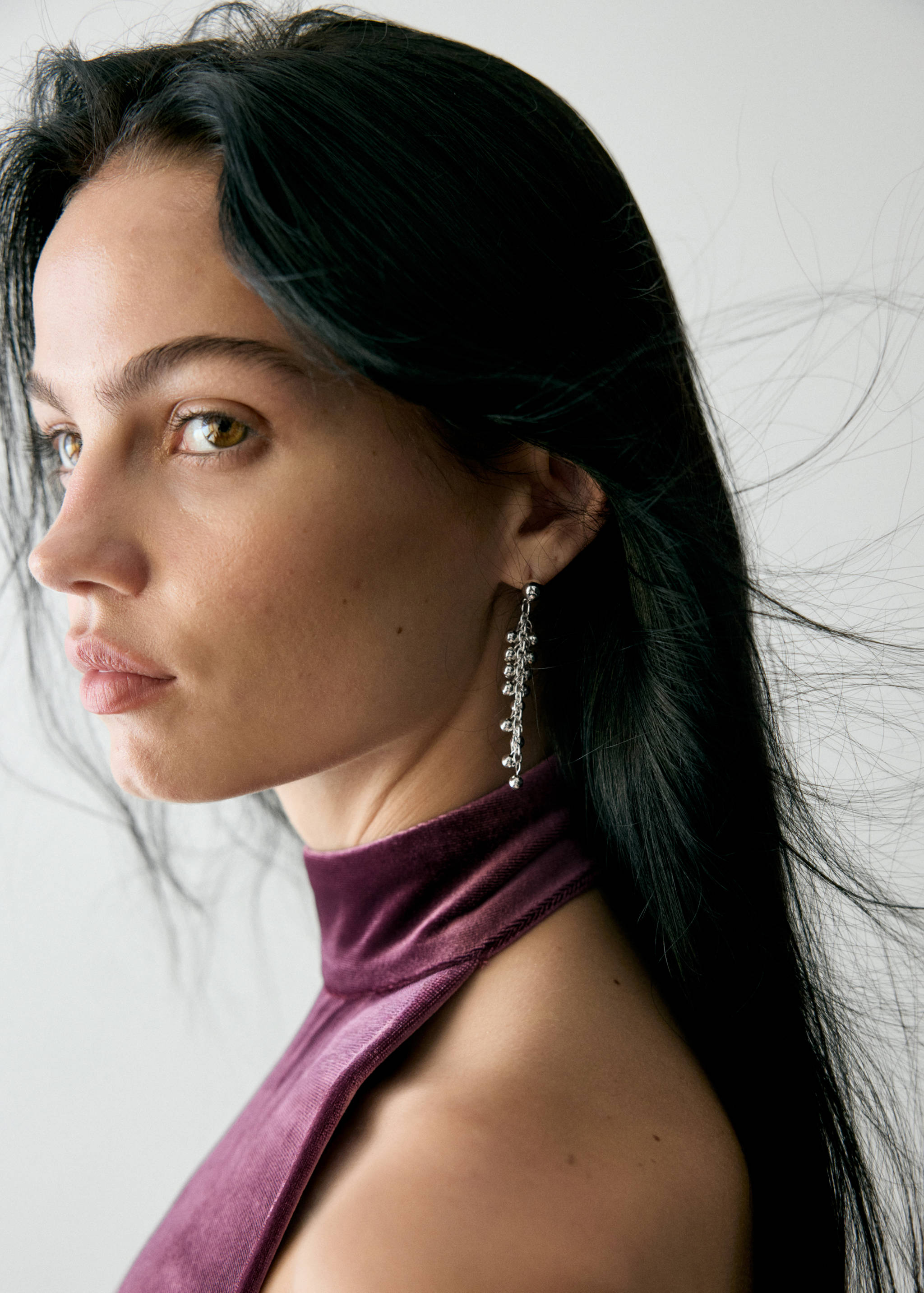 Silver dangle earring with delicate chains and beads, worn by a model.