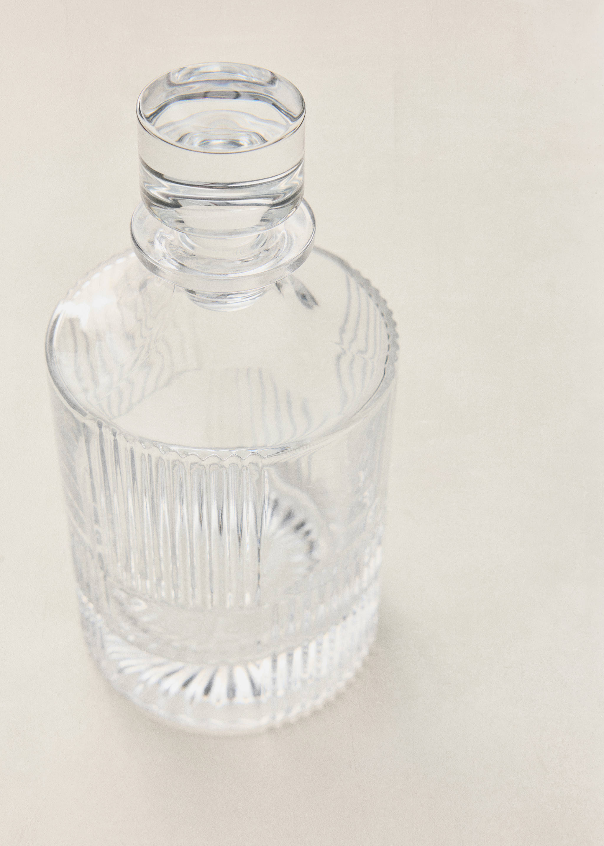 Clear glass bottle with vertical fluted texture and stopper.