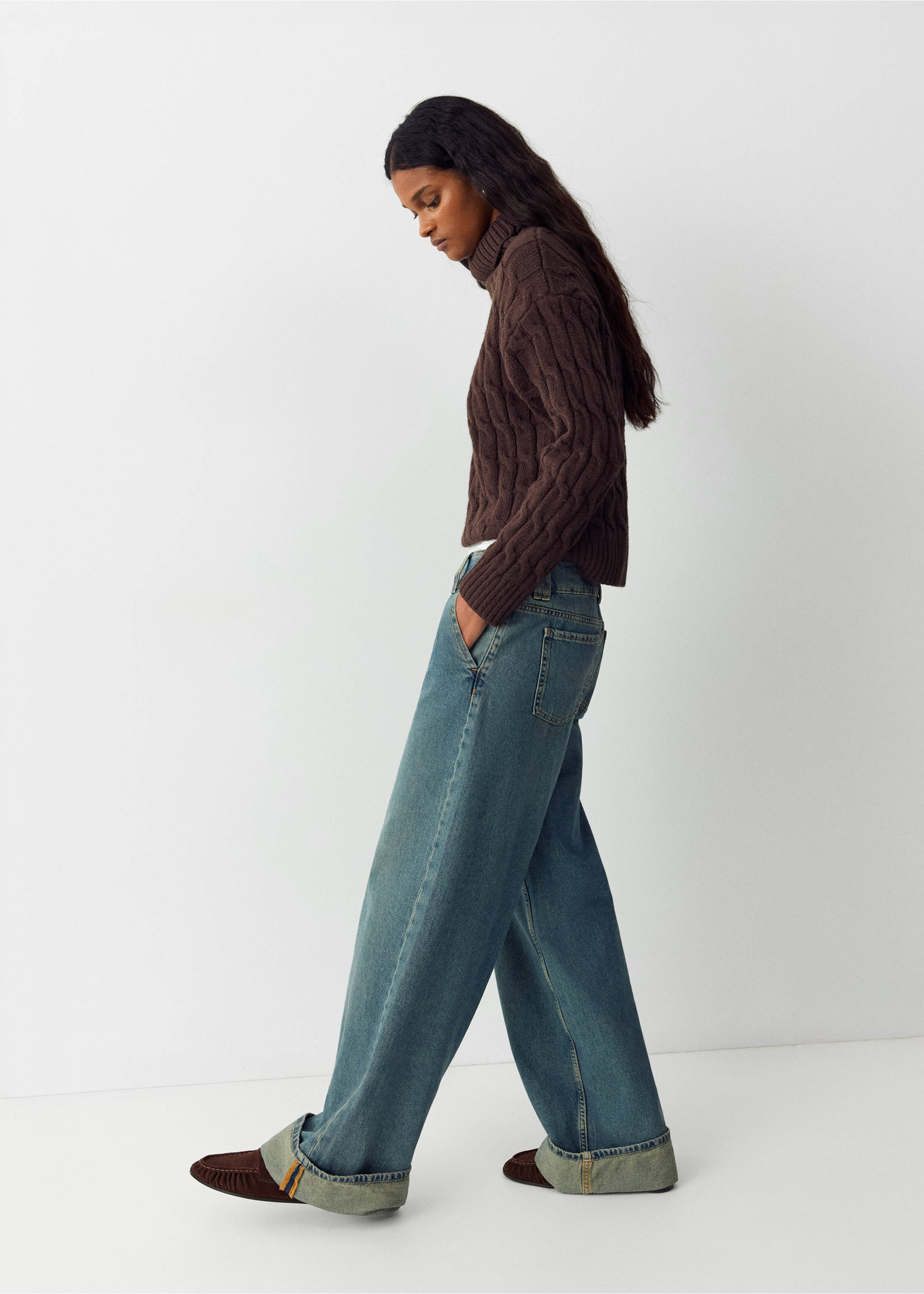 Blue denim trousers with wide turned-up cuffs, worn with a brown cable-knit turtleneck., Dark Vintage Blue. Ref: 37084789-01.
