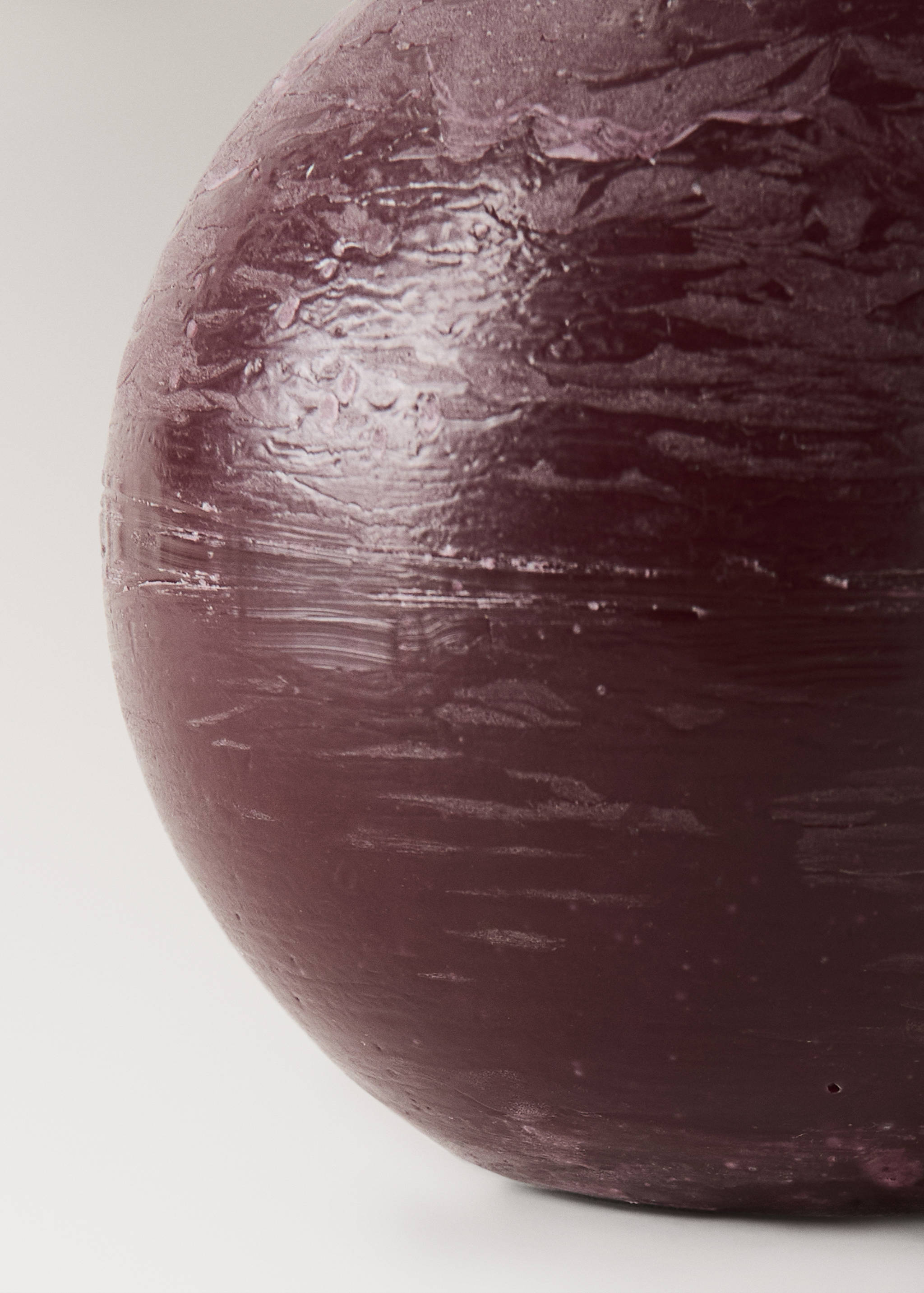 Close-up of a dark purple spherical candle with a textured surface.