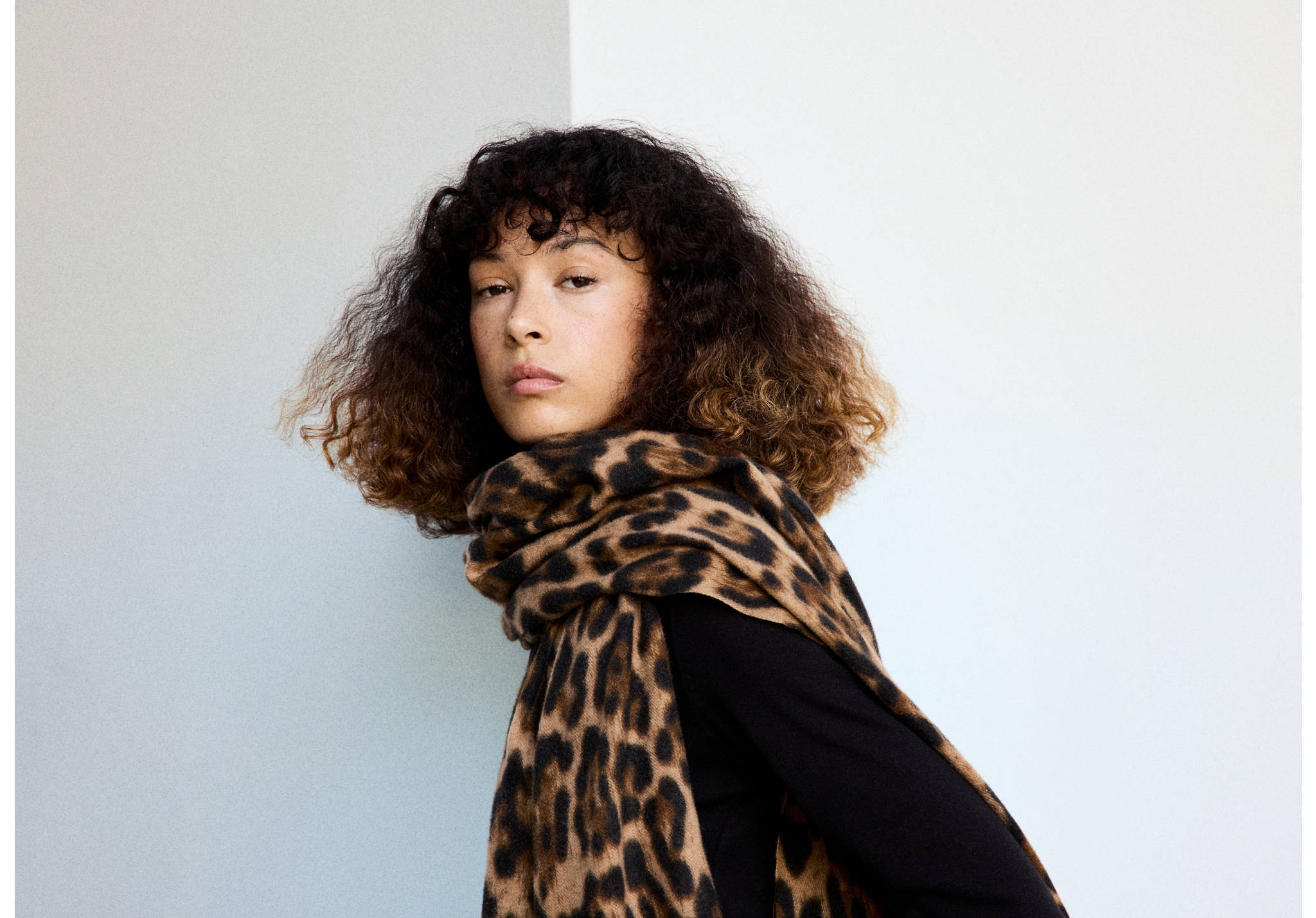 Leopard-print scarf in brown and black, worn draped around the neck.