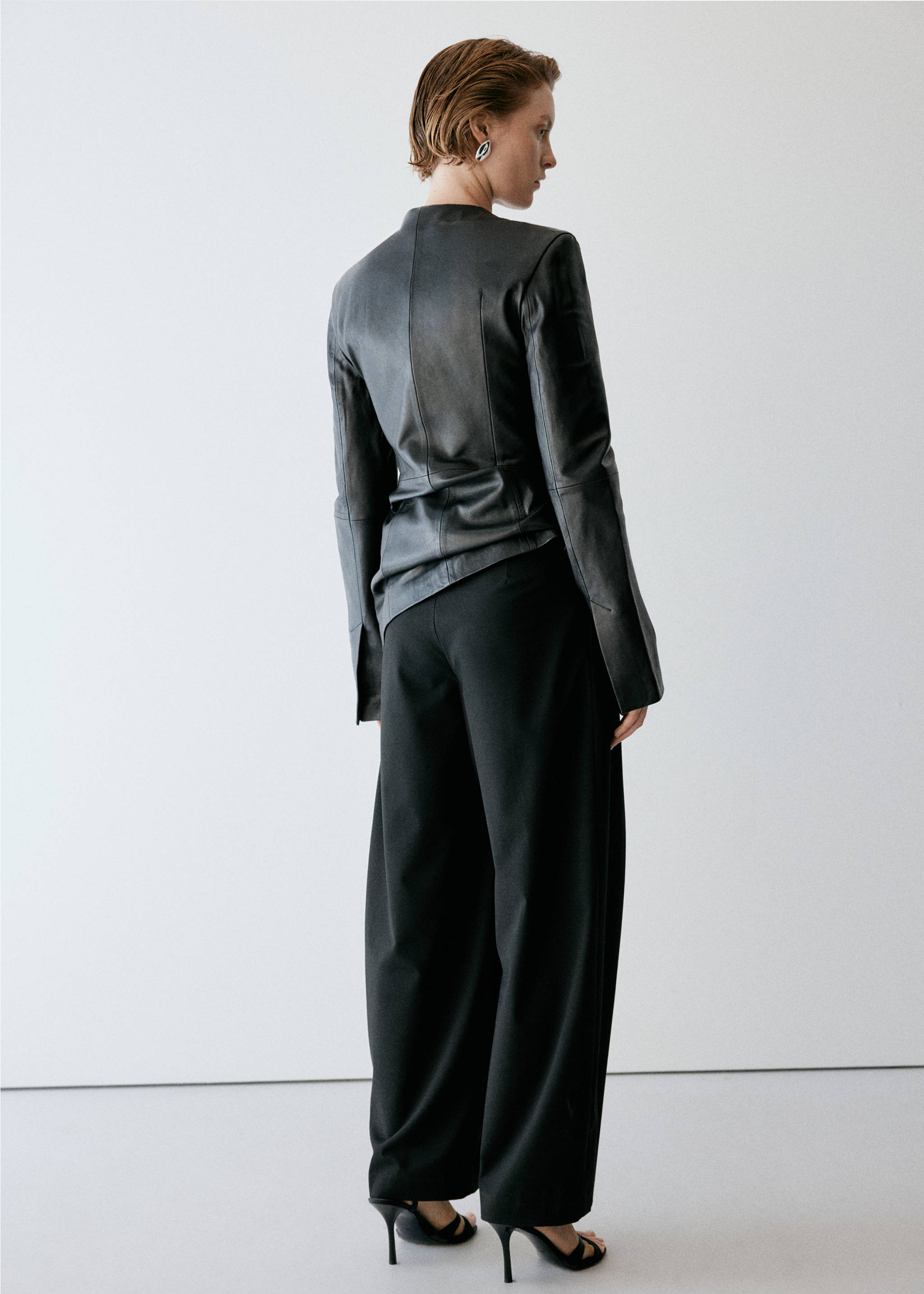 Black wide-leg trousers viewed from the back, worn with a black jacket., Black. Ref: 37085992-00.