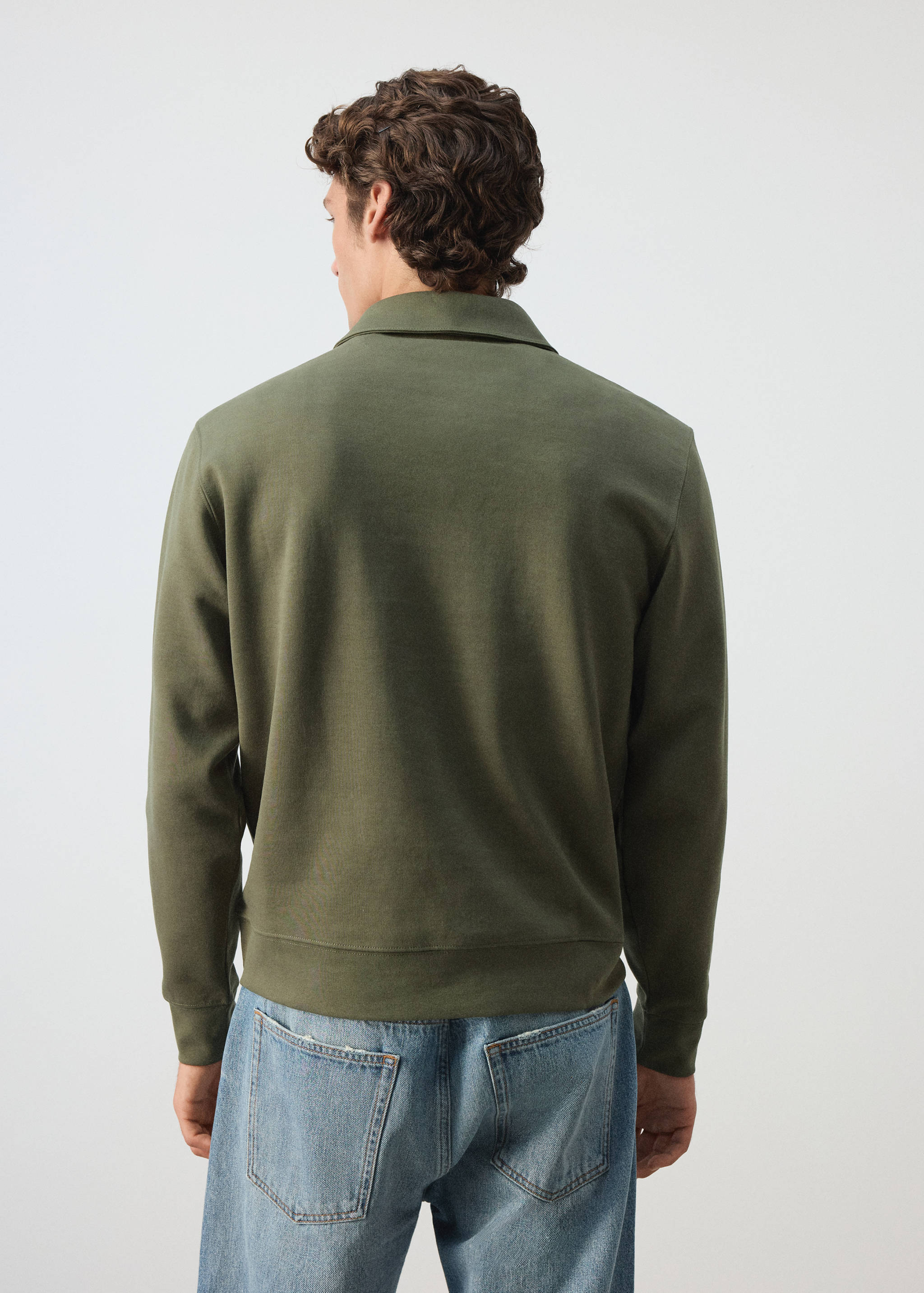 Back view of an olive green sweatshirt with a collar, worn with blue trousers.
