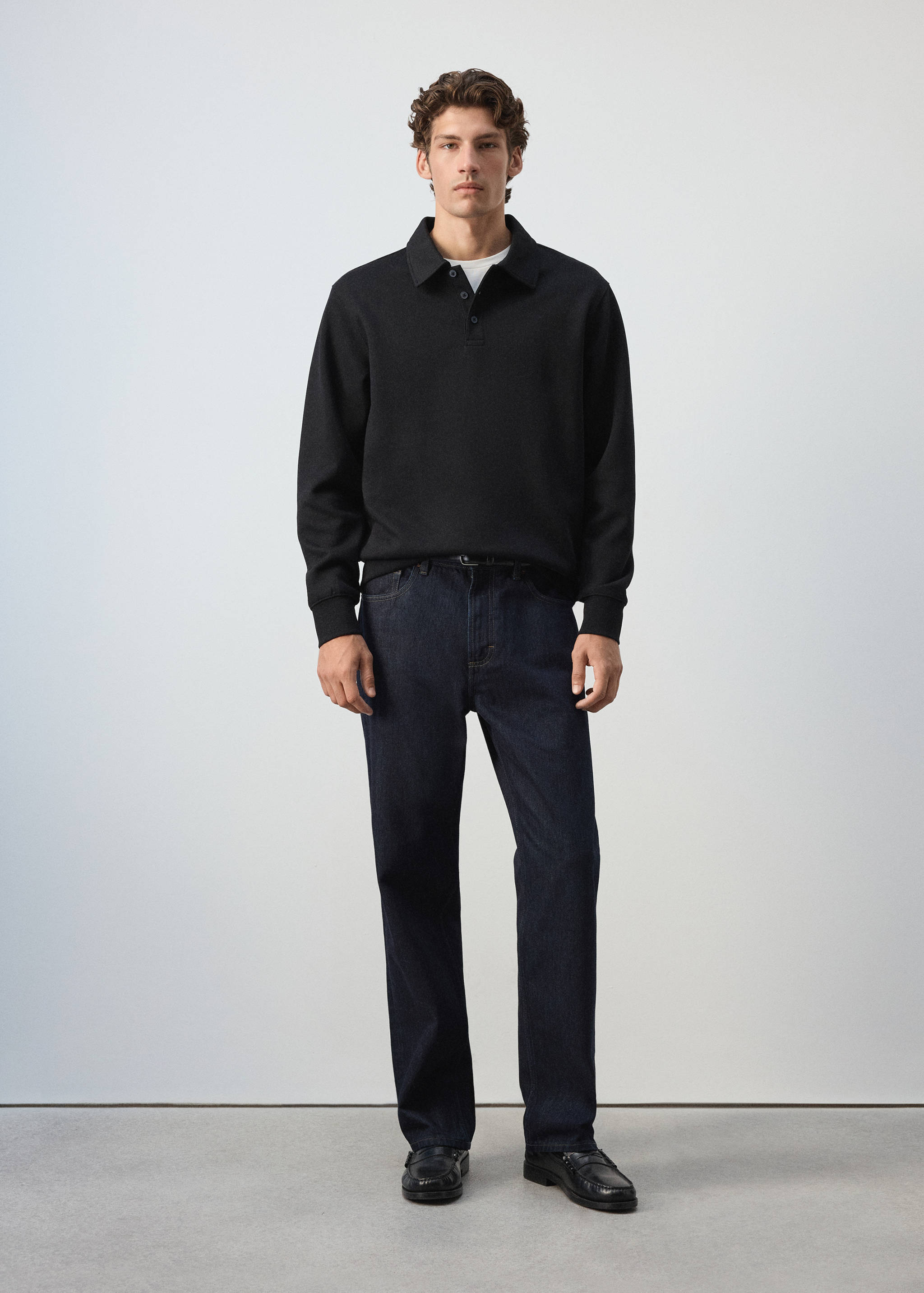 Black polo sweatshirt with long sleeves and ribbed trims worn with dark blue jeans.