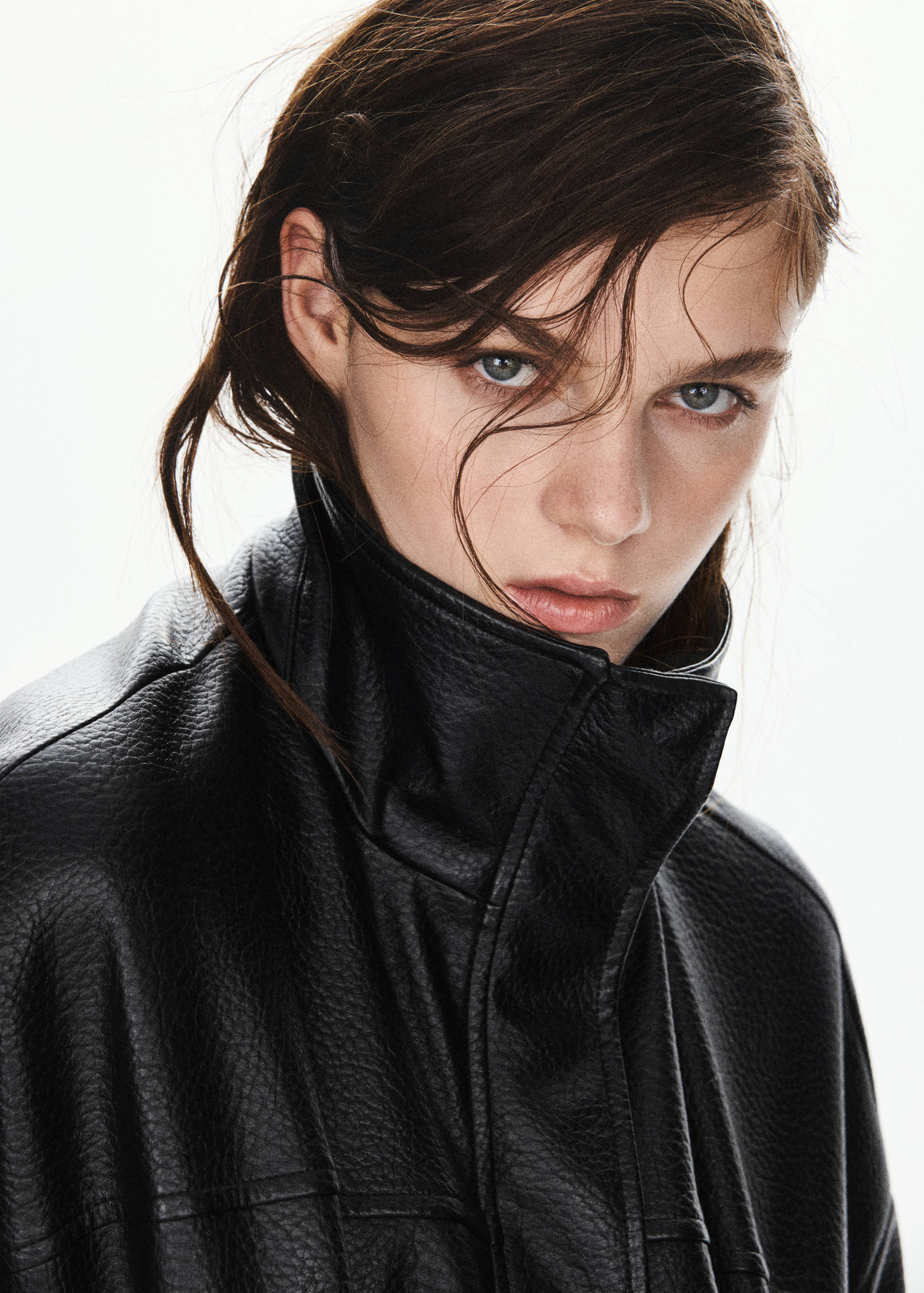 Close-up of a black textured jacket with a high collar, worn by a model.