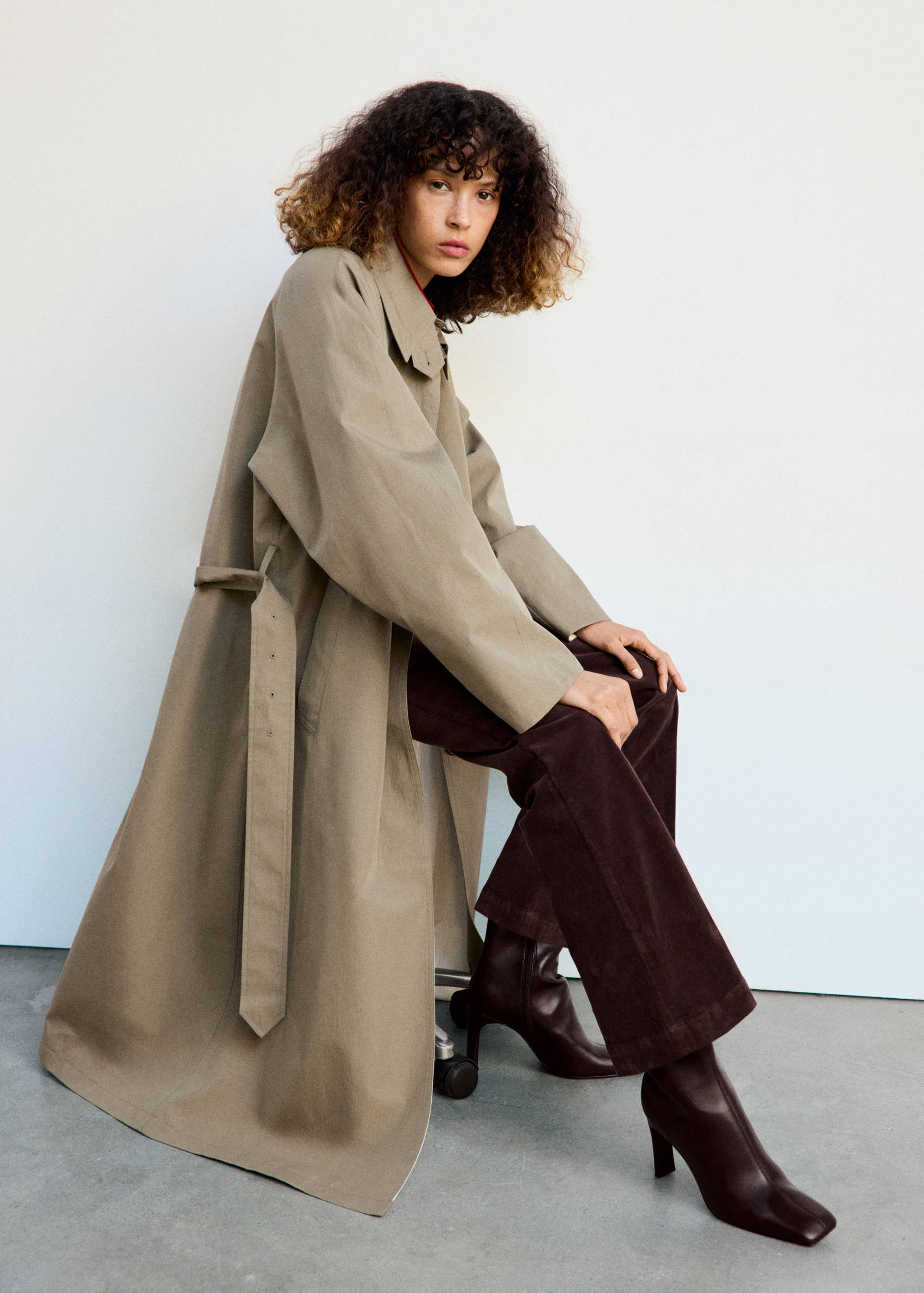 Dark brown heeled boots with a square toe, worn with corduroy trousers and a trench coat.