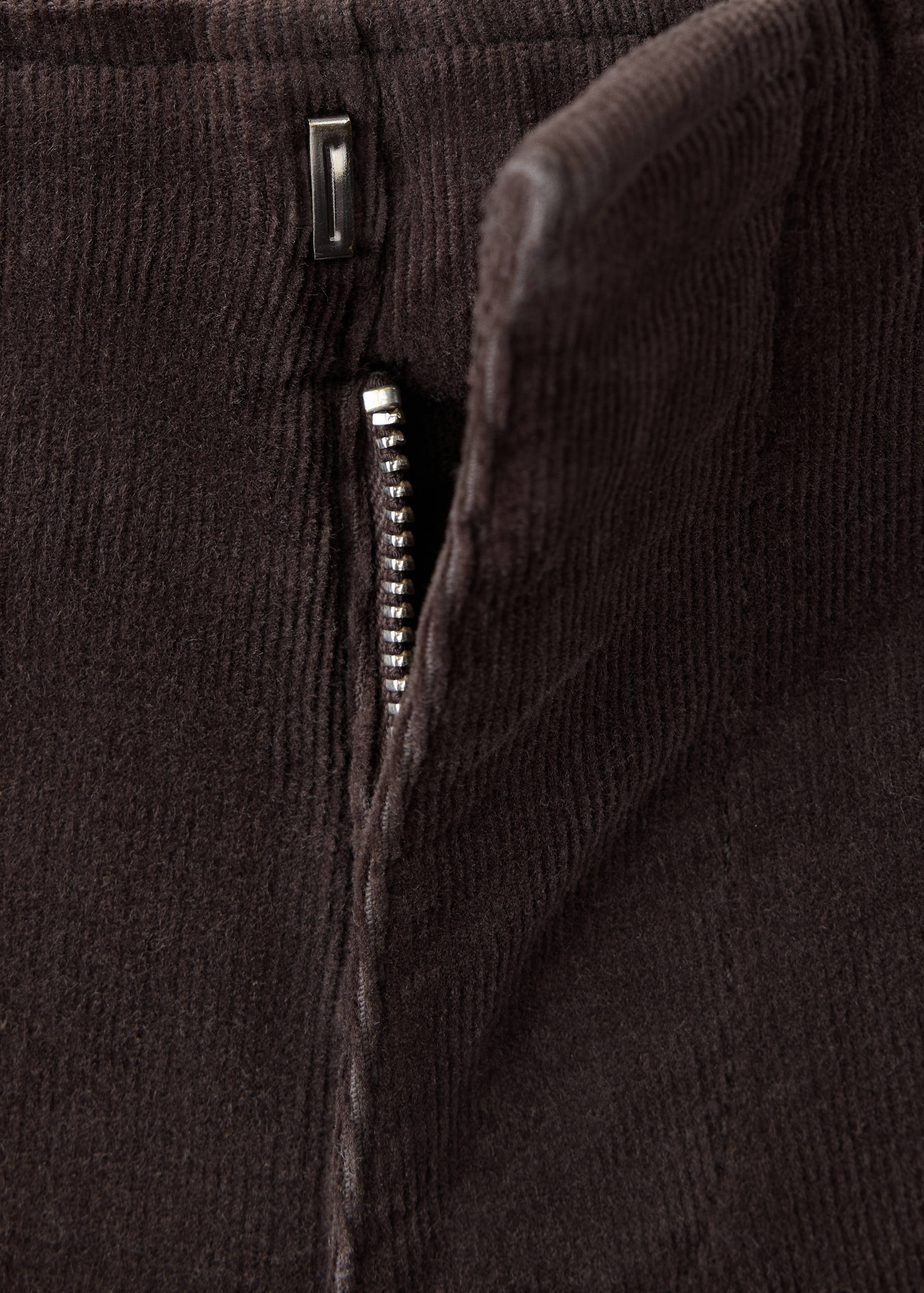 Close-up of the dark brown corduroy trousers zip closure.