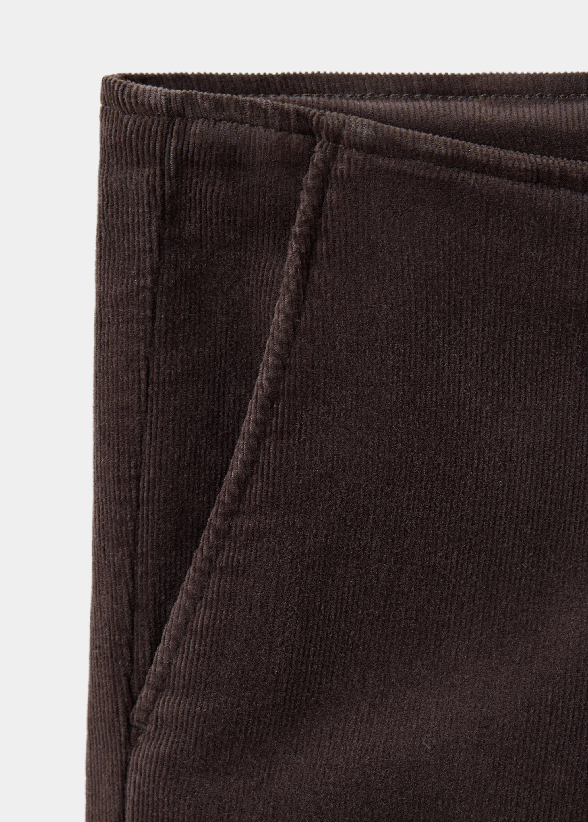 Close-up of dark brown corduroy trousers showing fabric detail.