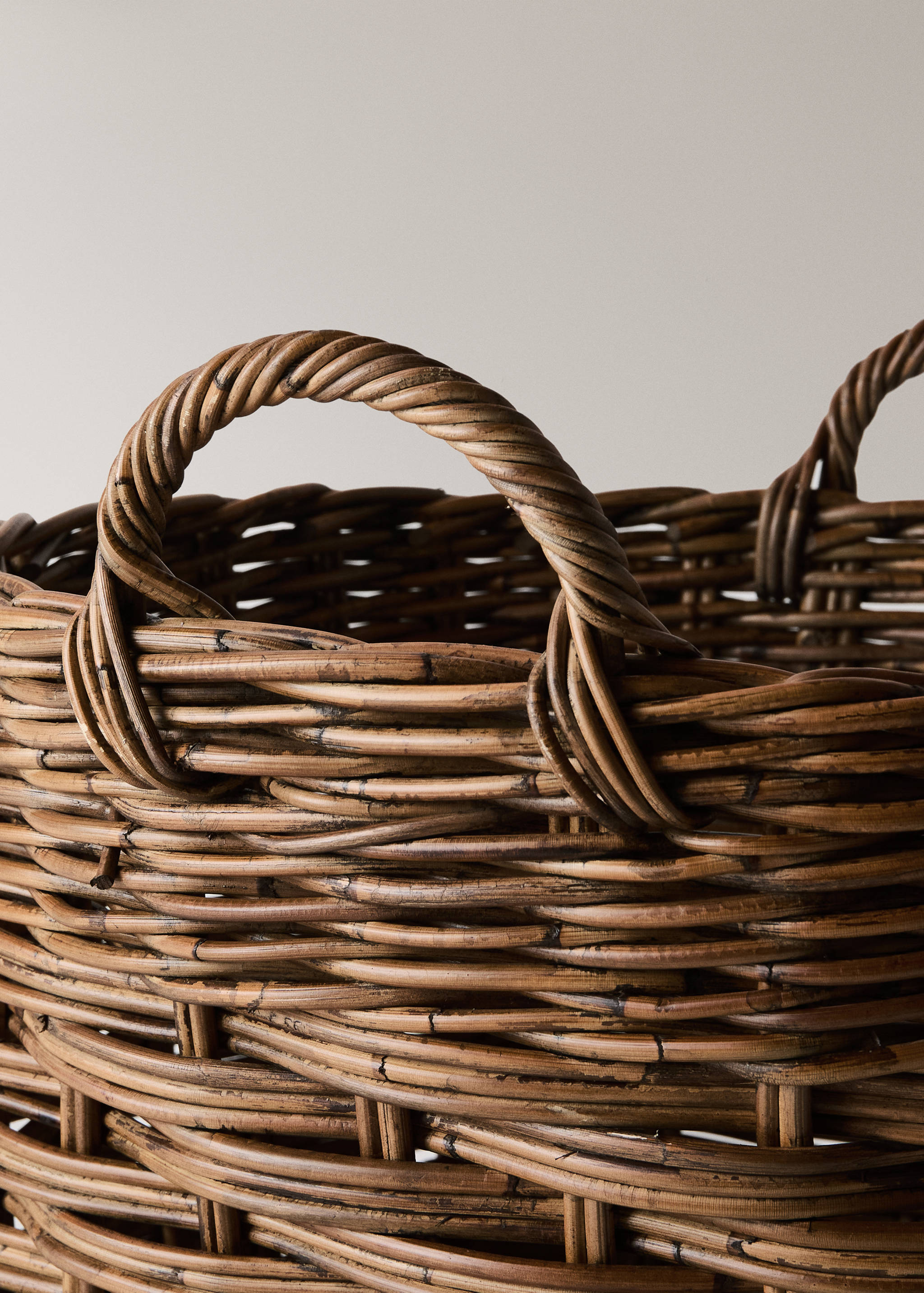 Close-up of a brown woven rattan basket showing the textured weave and handle detail.