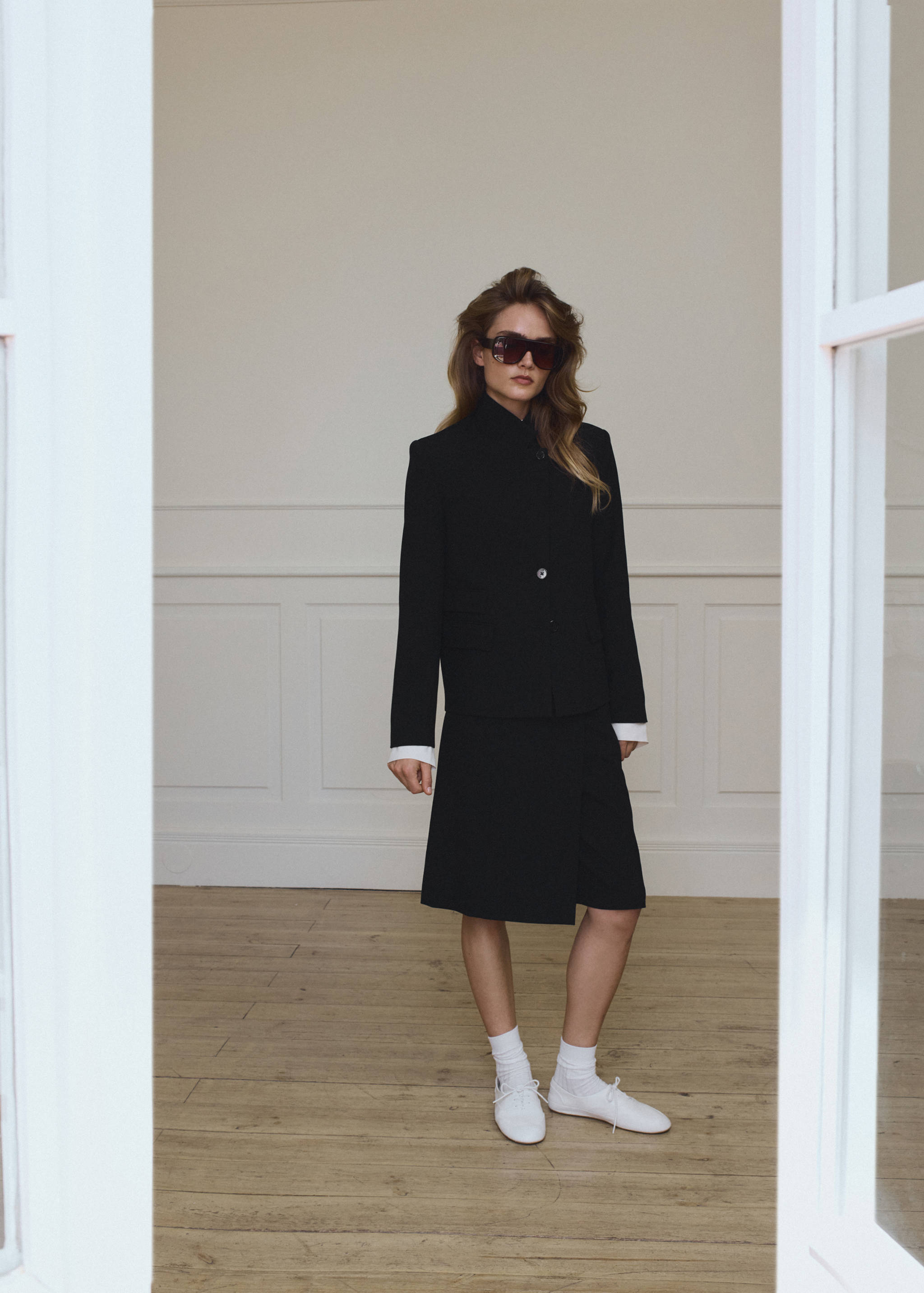 Black blazer with high collar, worn with a matching skirt.