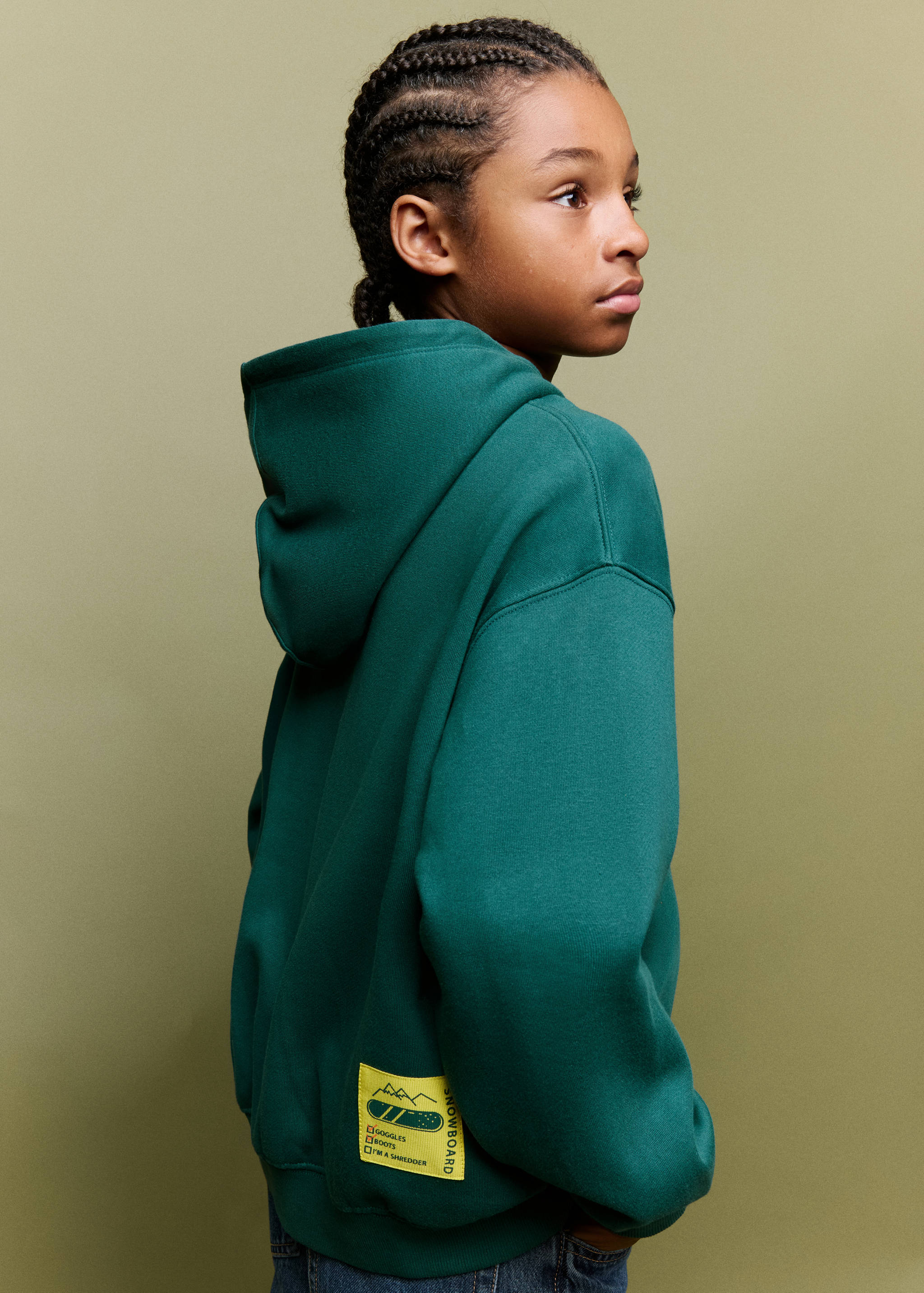 Dark green hooded sweatshirt with a back hem label, viewed from the side.