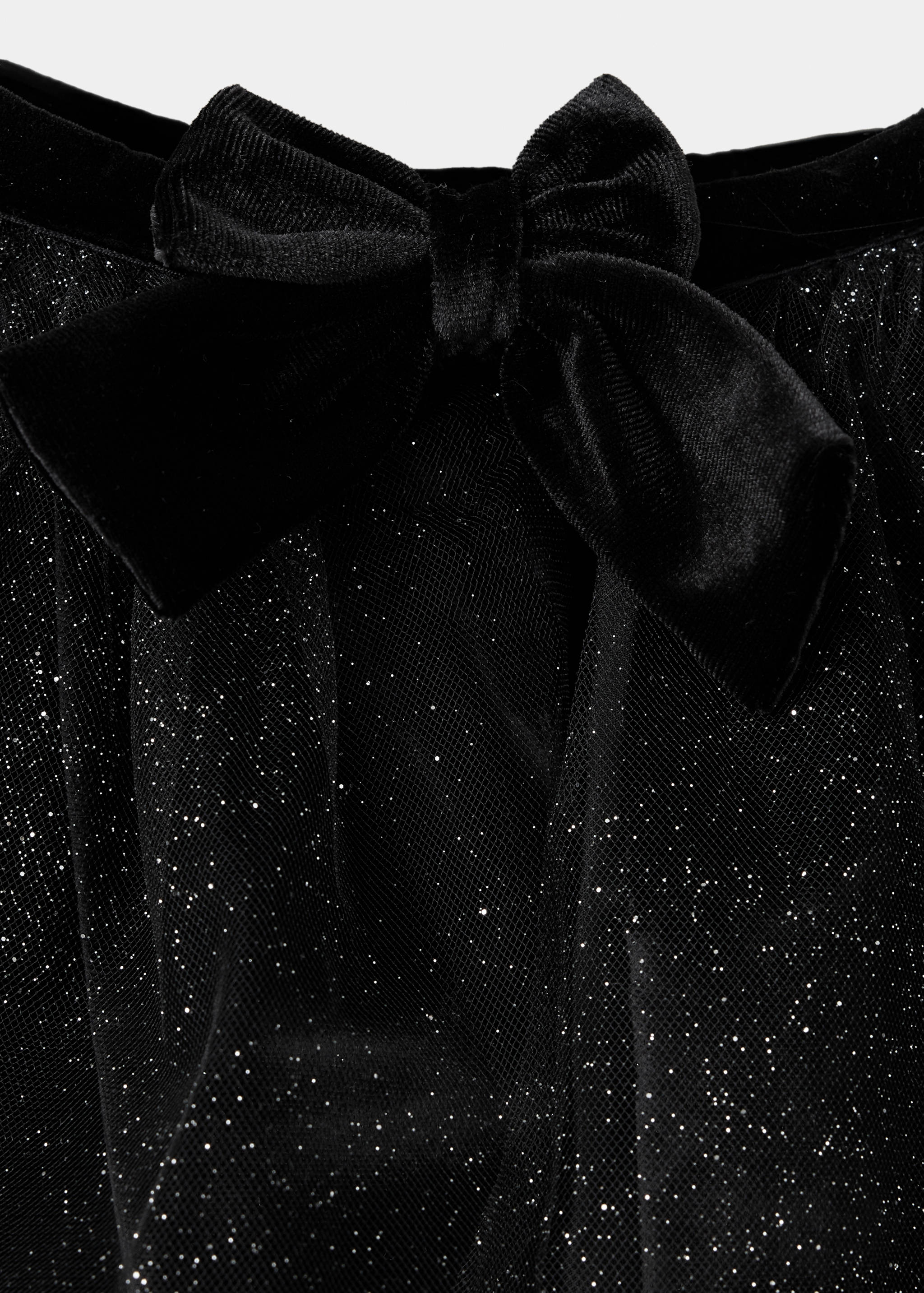 Detalle de tejido de capa negra con acabado brillante y lazo de terciopelo.