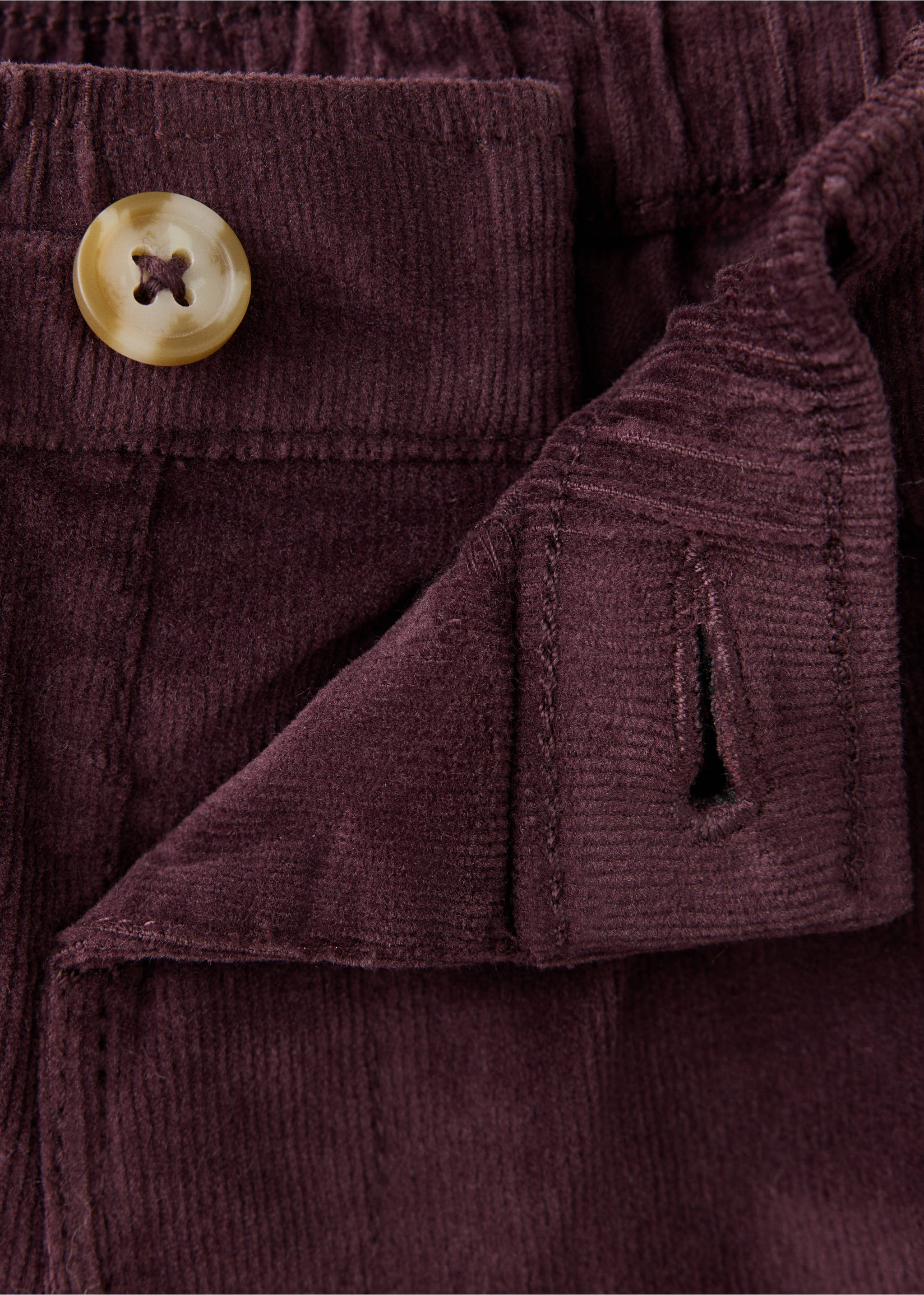 Close-up of a dark purple corduroy trousers waistband detail showing the button fastening., Maroon. Ref: 37087124-00.