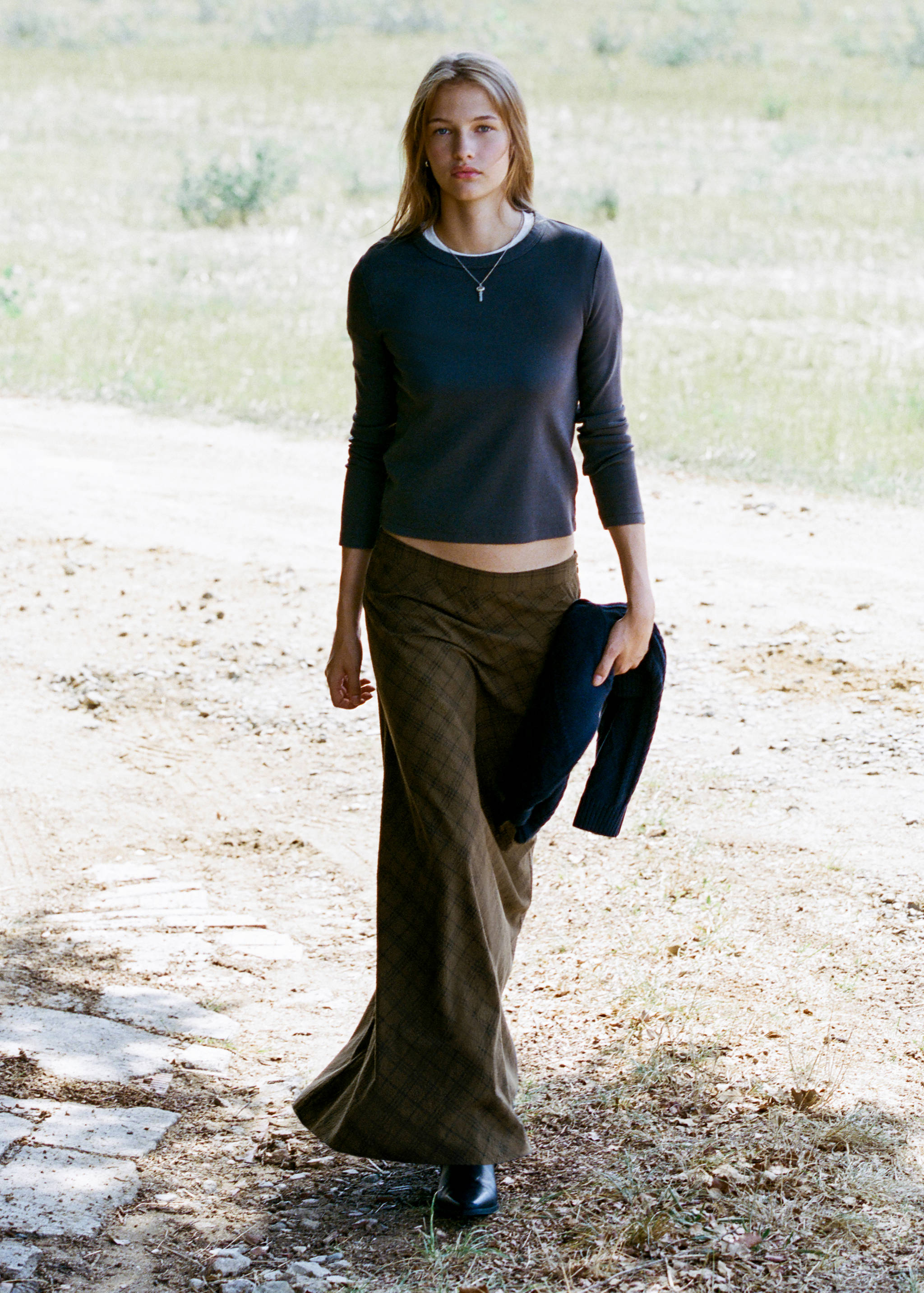 Brown plaid long skirt with a low rise, worn with a dark grey long-sleeved top.