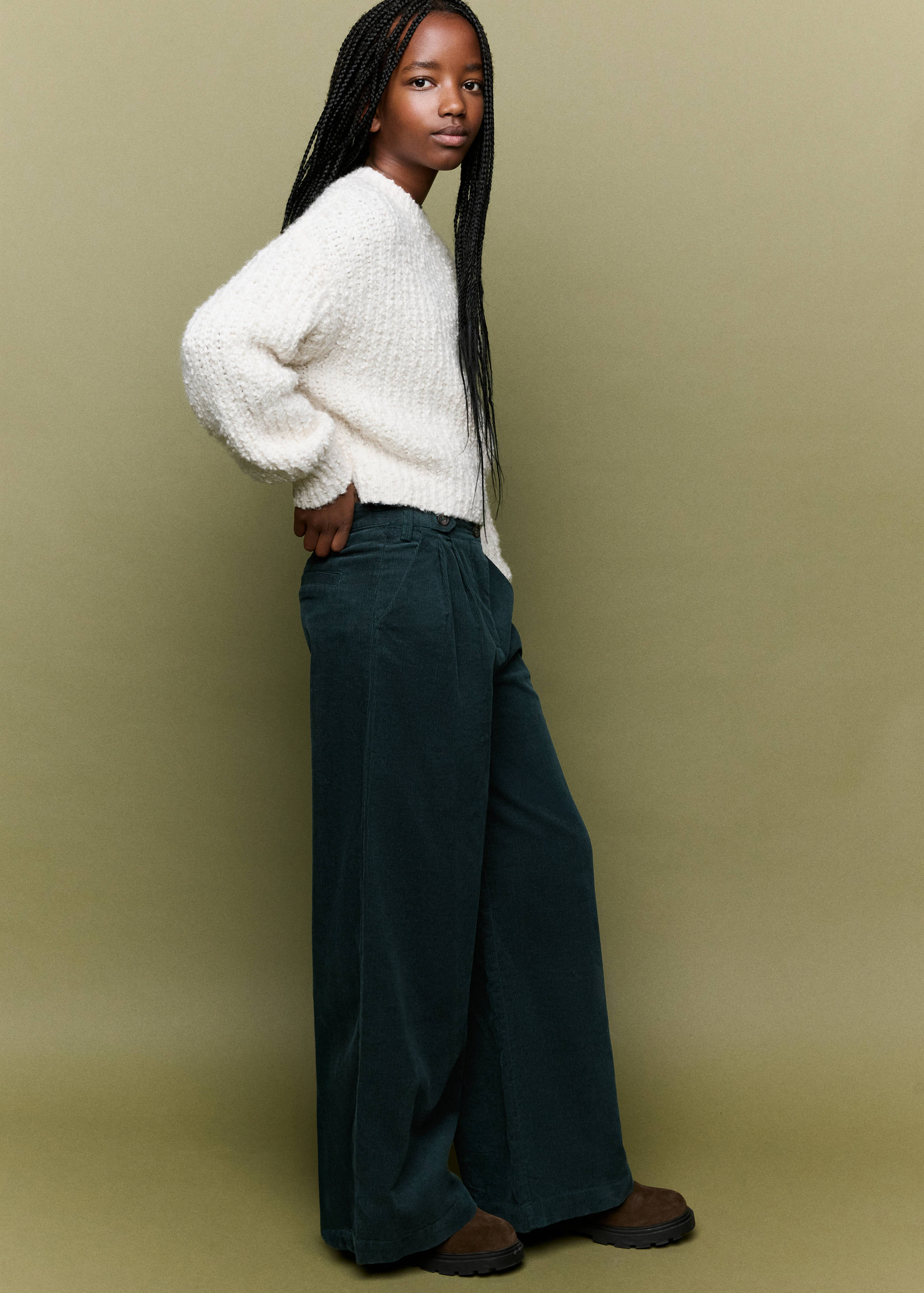 Dark green wide-leg trousers with front pleats, worn with a textured cream sweater.