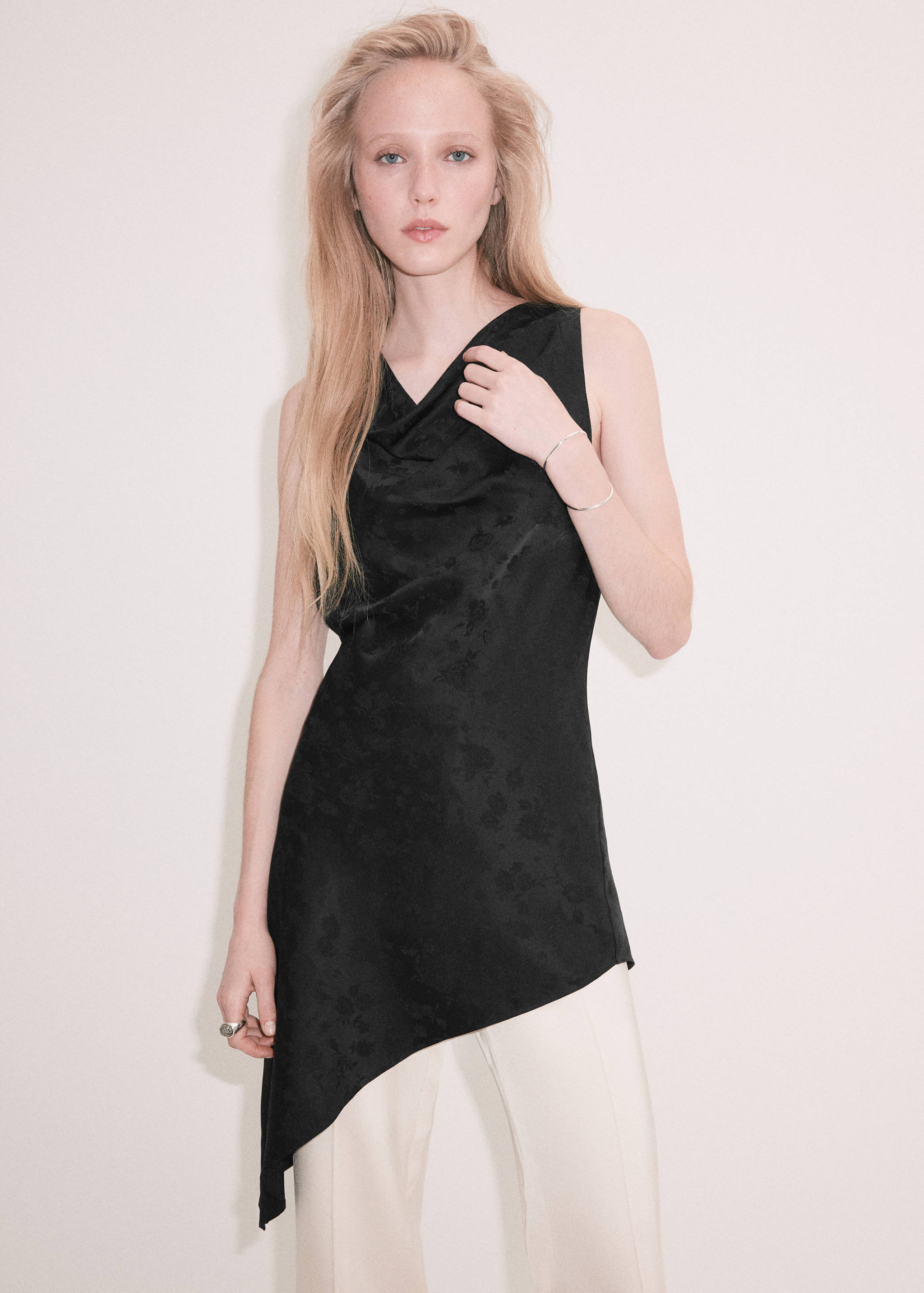 Black sleeveless cowl-neck top with an asymmetrical hem