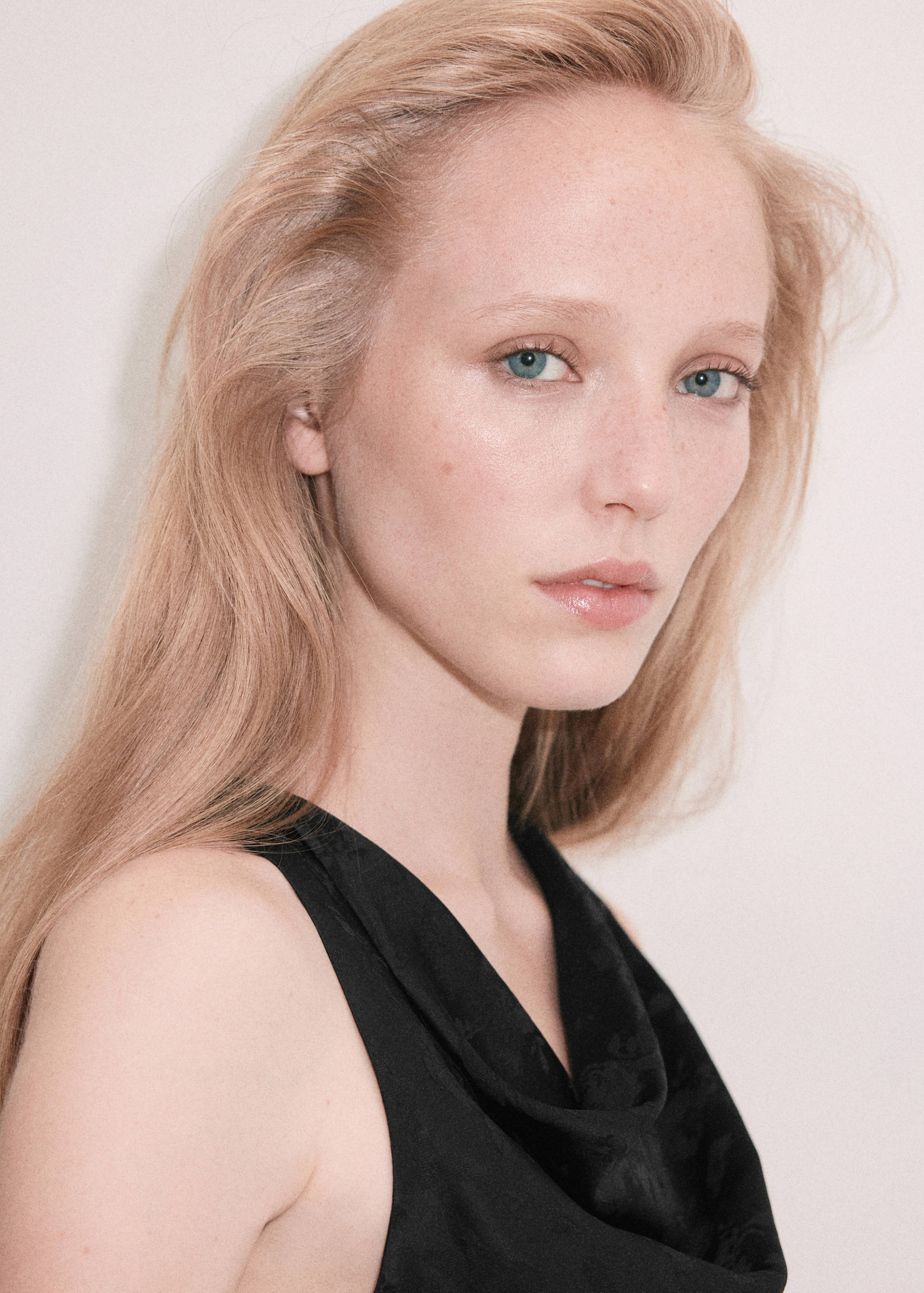 Close-up of a black sleeveless top with a draped cowl neckline worn by a model.