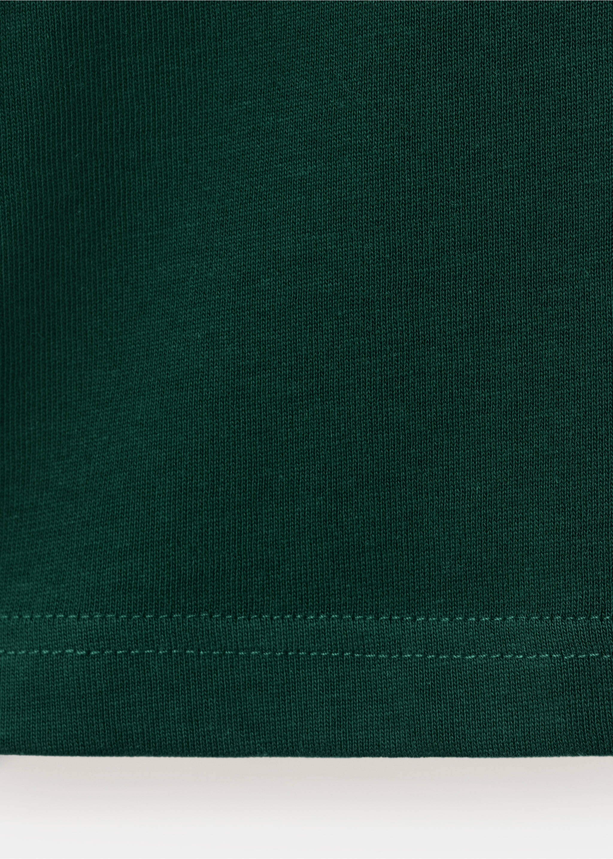 Close-up of the dark green knit fabric and hem of a t-shirt., Dark Green. Ref: 37087787-00.