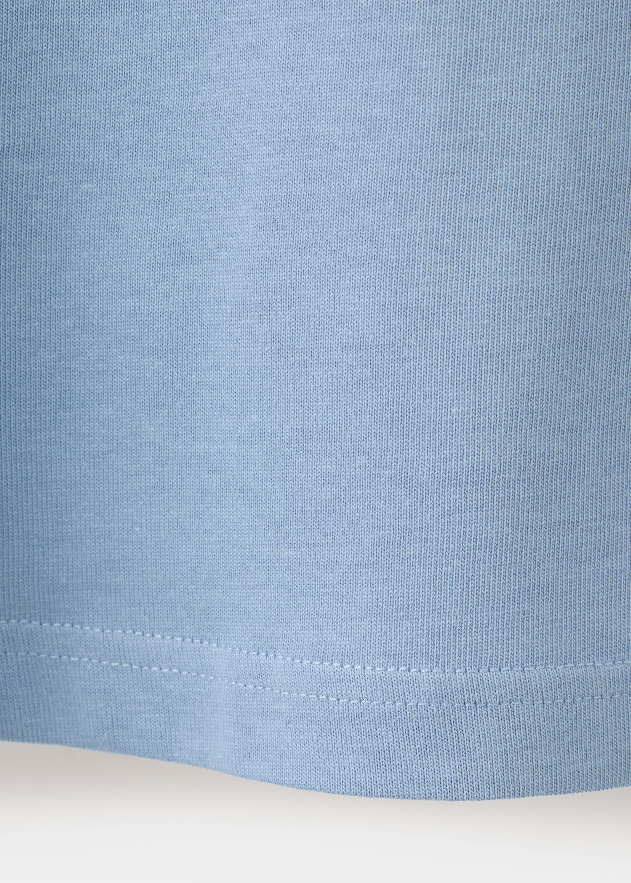 Close-up of the light blue t-shirt fabric texture and stitched hem.