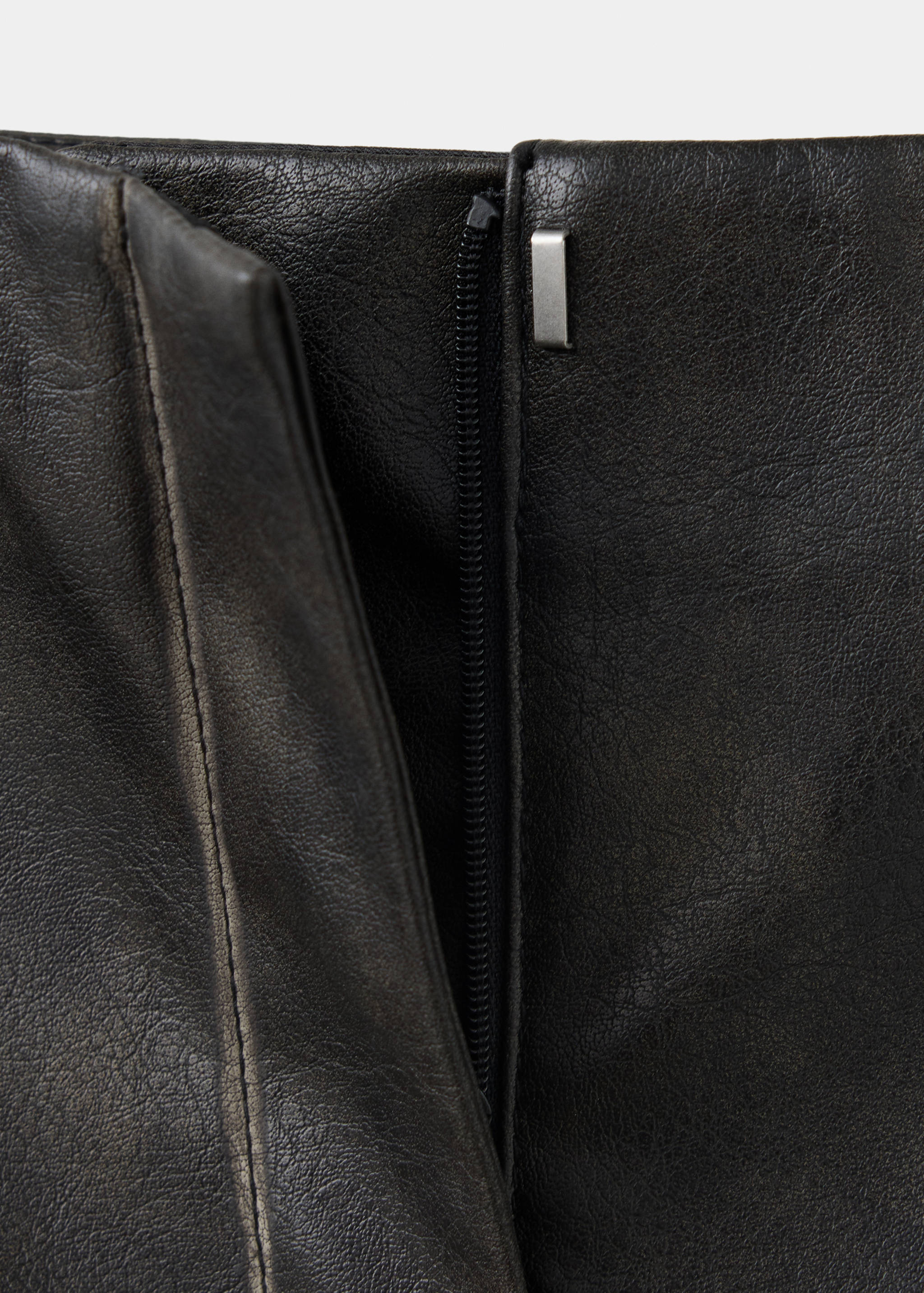 Close-up of dark grey trousers showing the waistband zip and clasp detail.