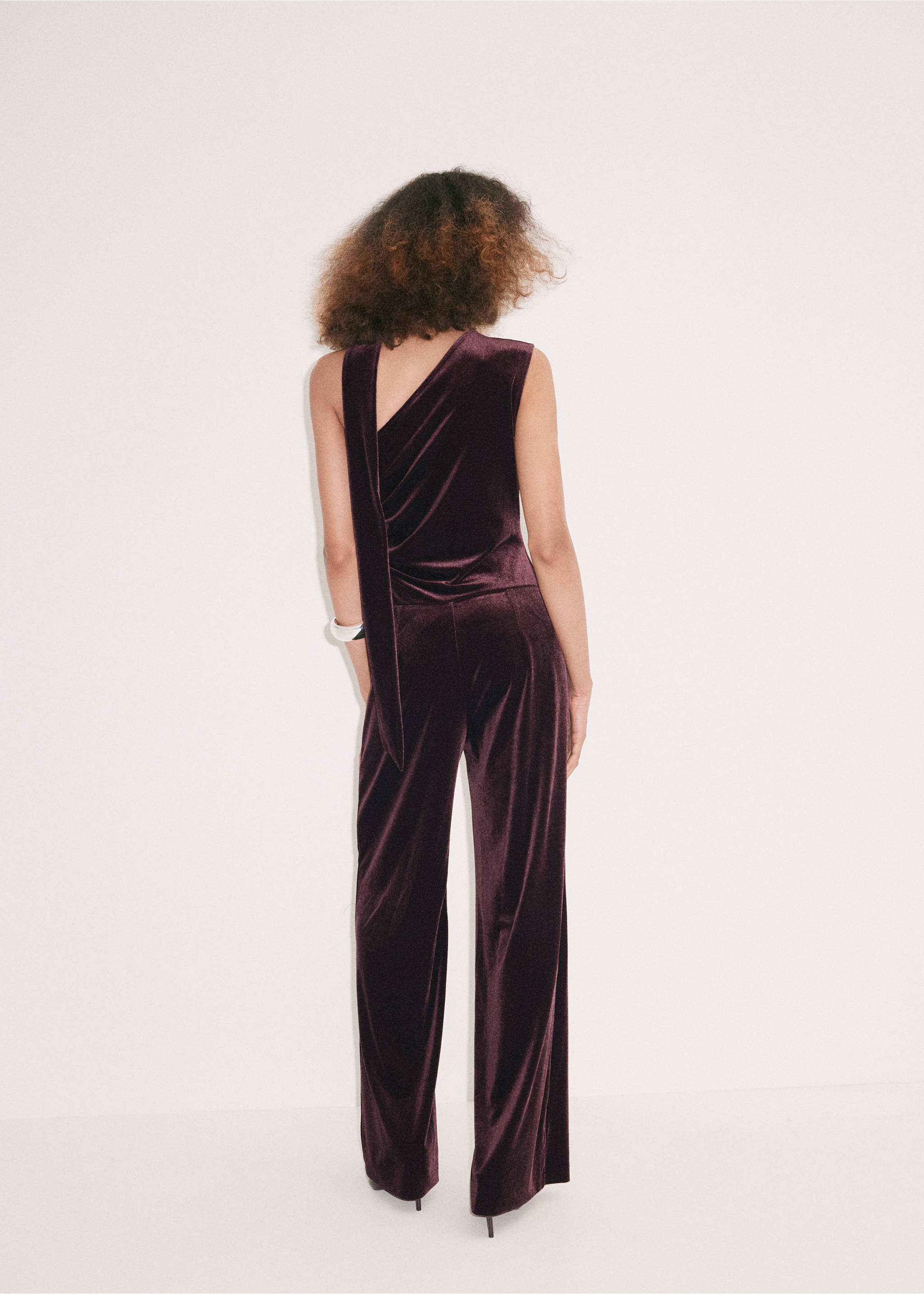 Dark plum purple velvet jumpsuit seen from the back, featuring an asymmetrical sleeveless bodice and wide-leg trousers., Burgundy. Ref: 37087791-00.