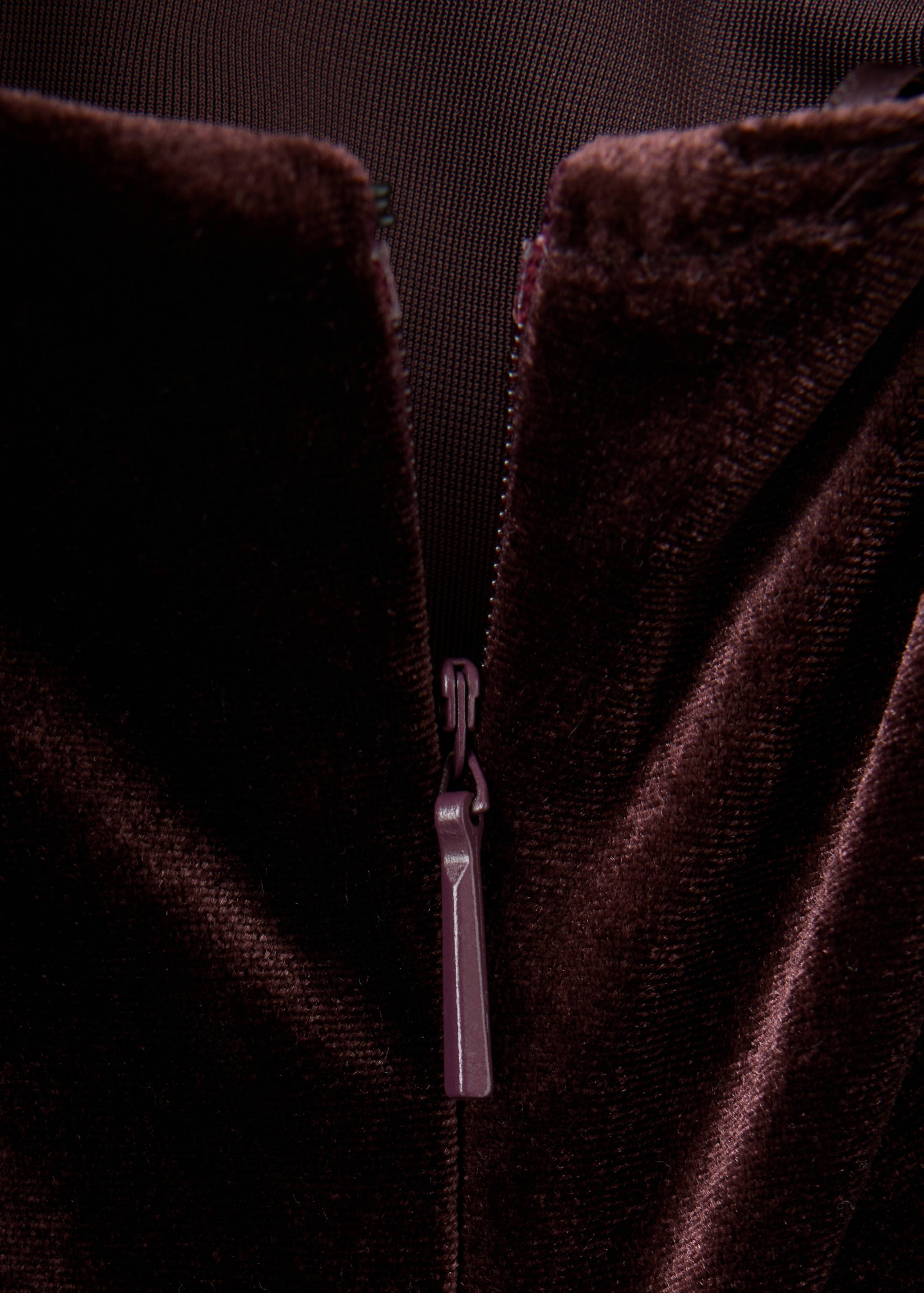 Close-up of the zipper detail on a dark brown velvet jumpsuit.