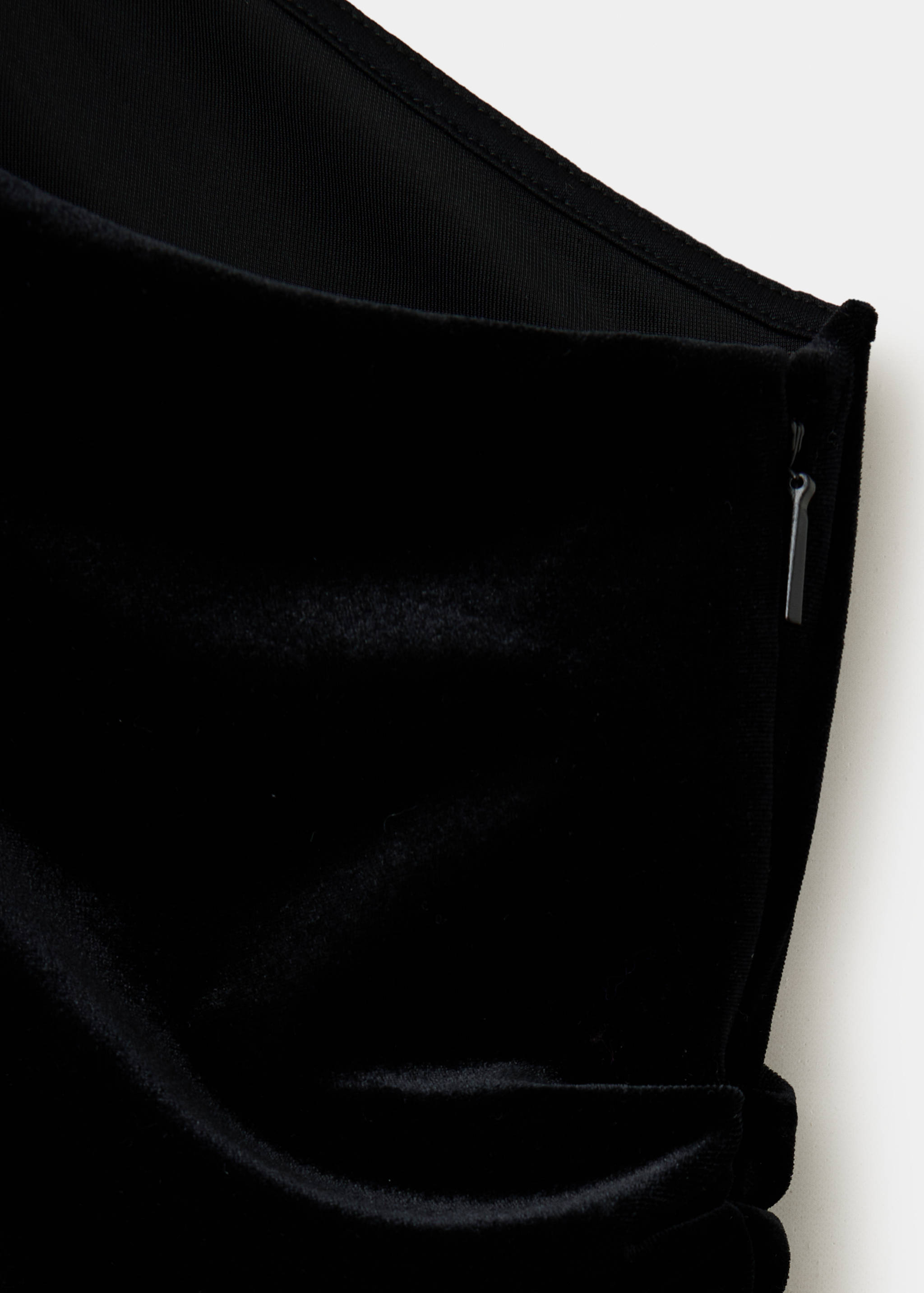 Close-up of a black velvet jumpsuit showing the side zipper detail.