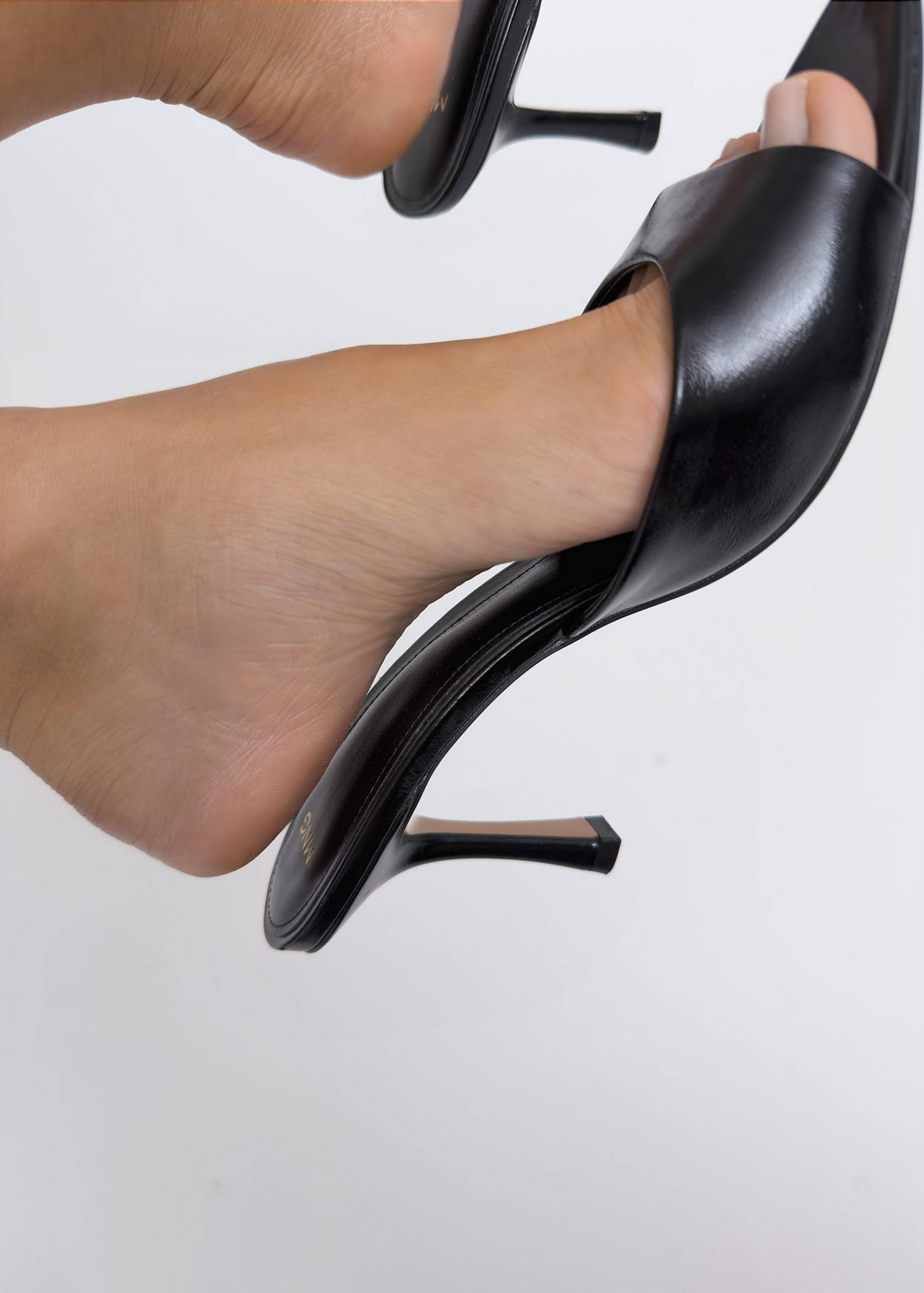 Black heeled sandals with wide upper straps and slim stiletto heels.