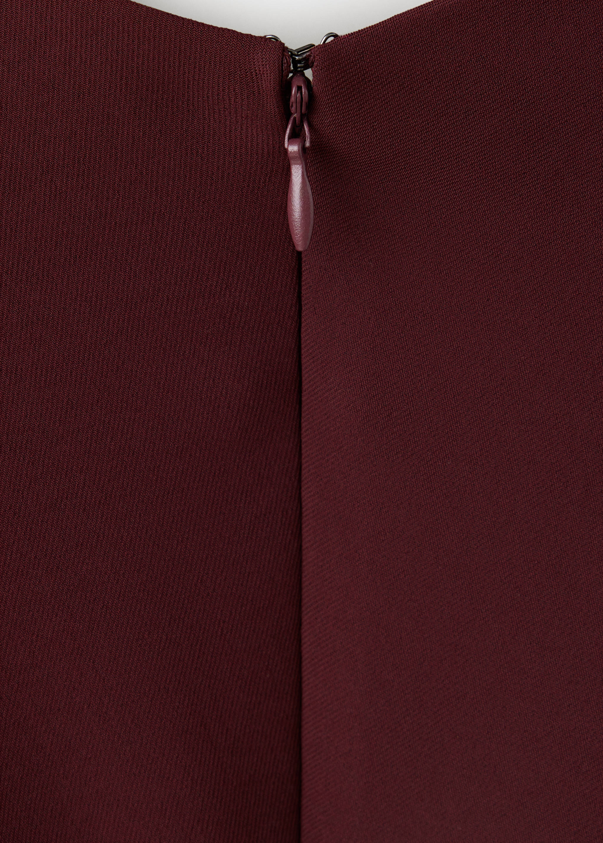 Burgundy dress zip detail showing a concealed zipper and fabric-covered puller.