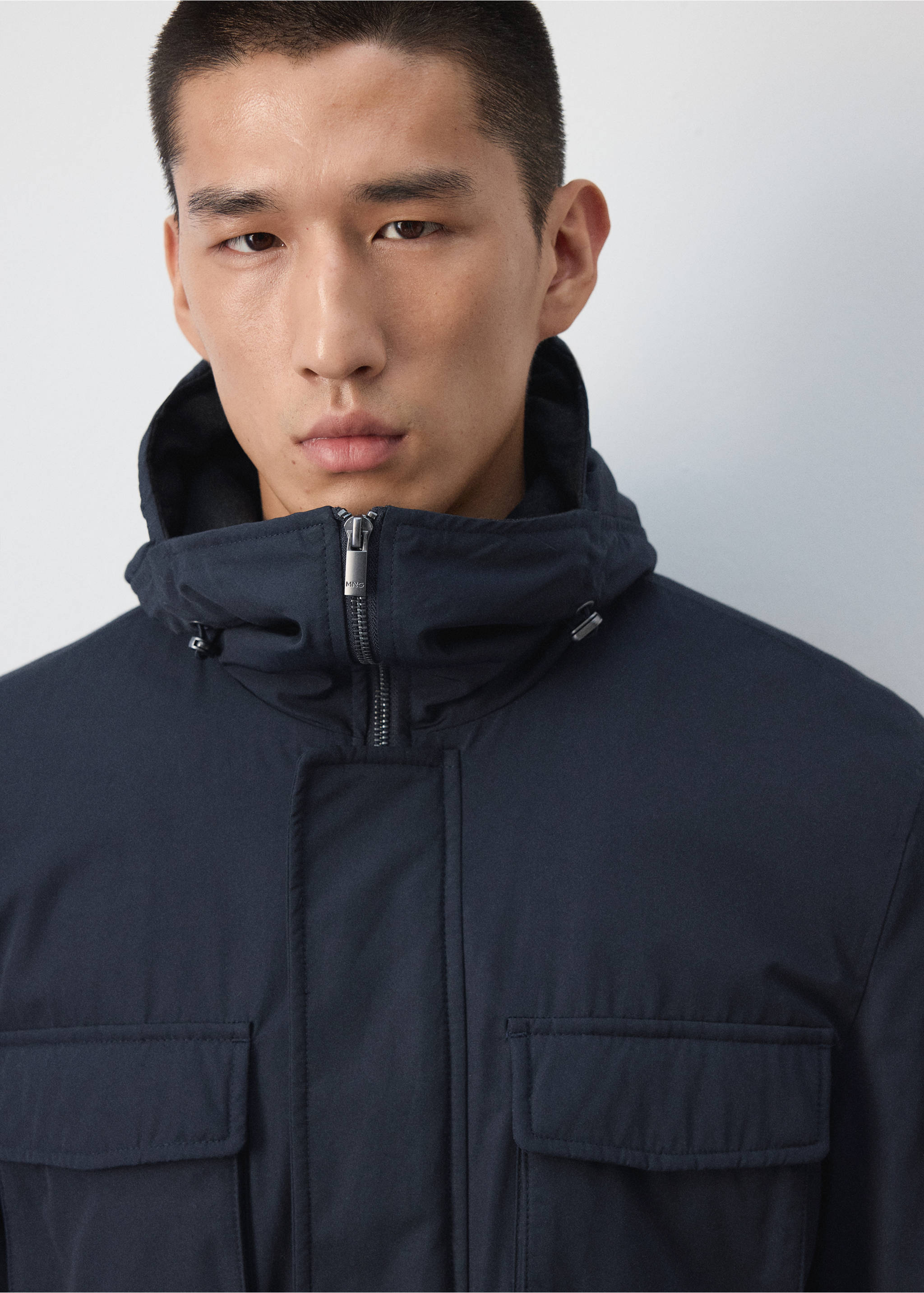 Close-up of a dark navy blue parka with a high collar, hood, and utility pockets., Night Blue. Ref: 37087883-00.