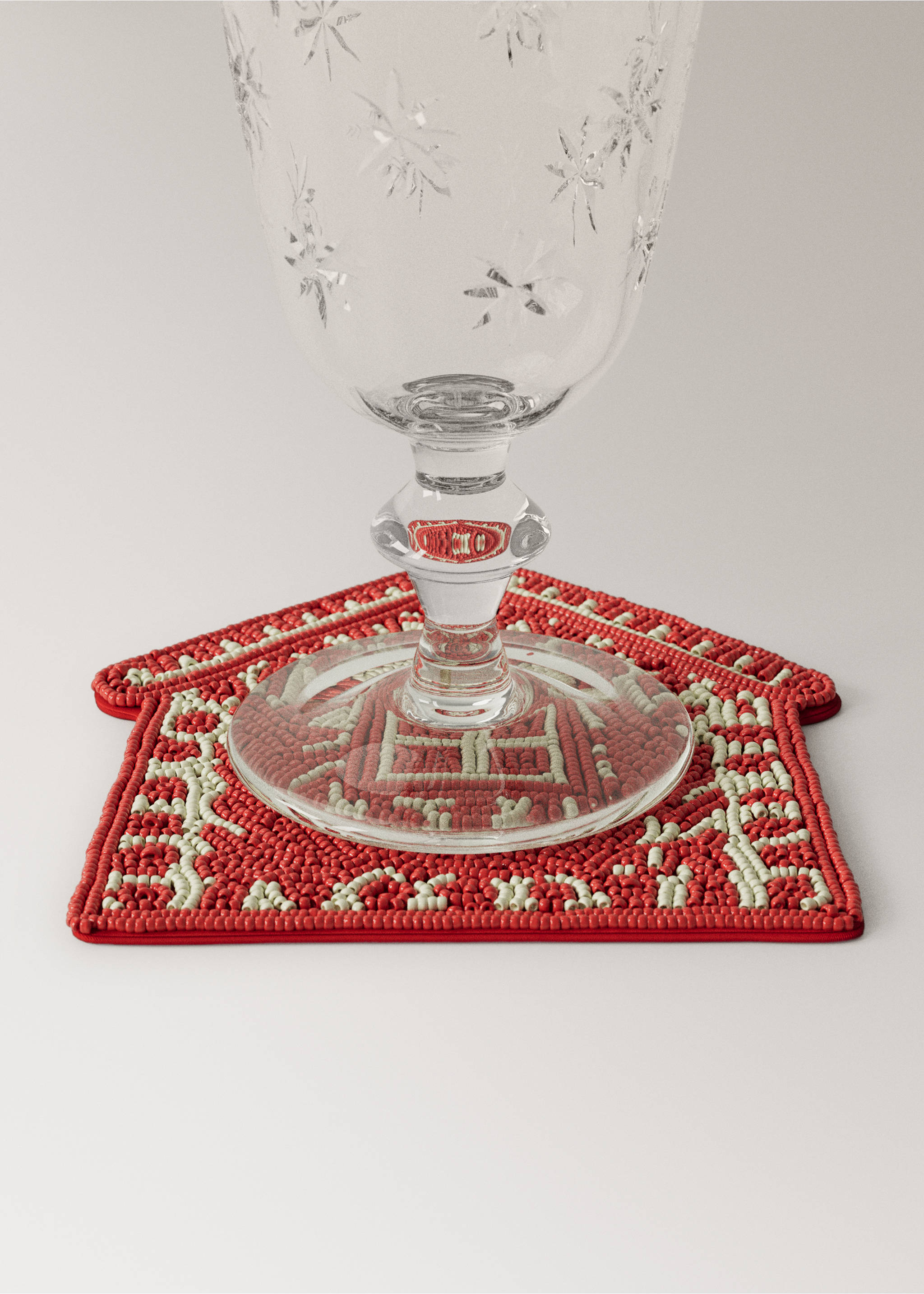 Red and off-white beaded house-shaped coaster with a glass on top., Red. Ref: 37087893-00.