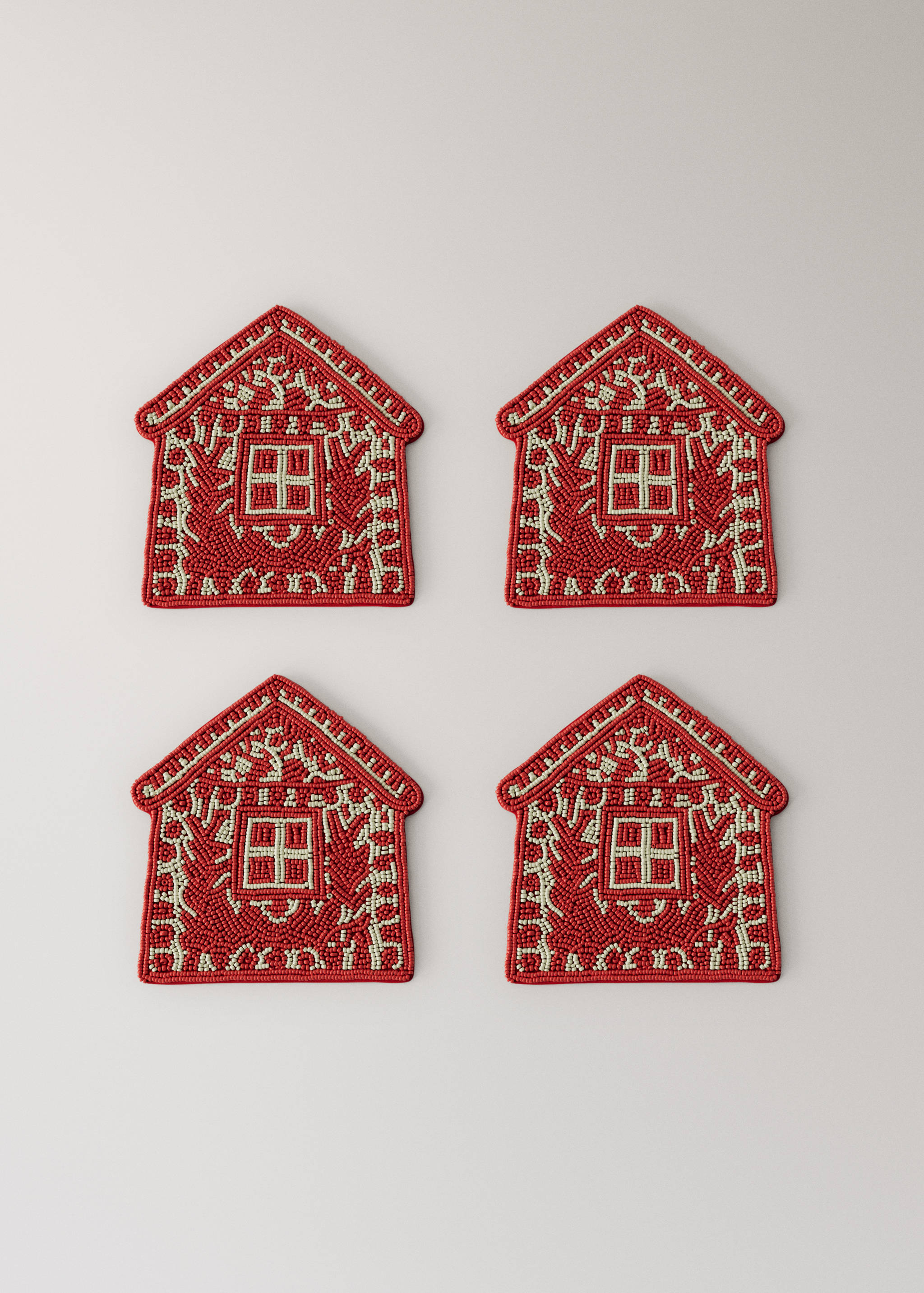 Set of four red house-shaped beaded coasters with cream detailing.