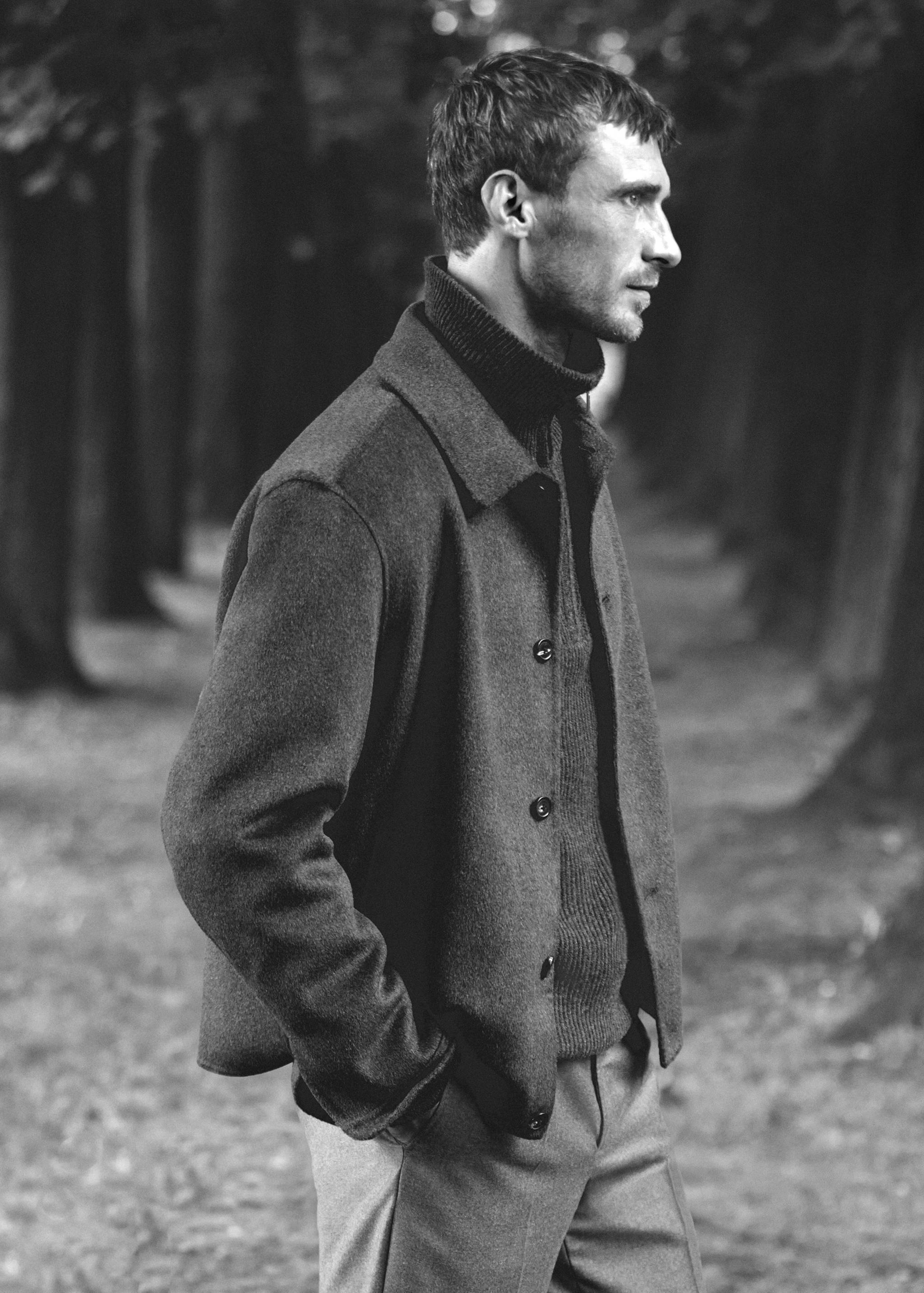 Dark jacket with collar and buttons worn in an outdoor setting.