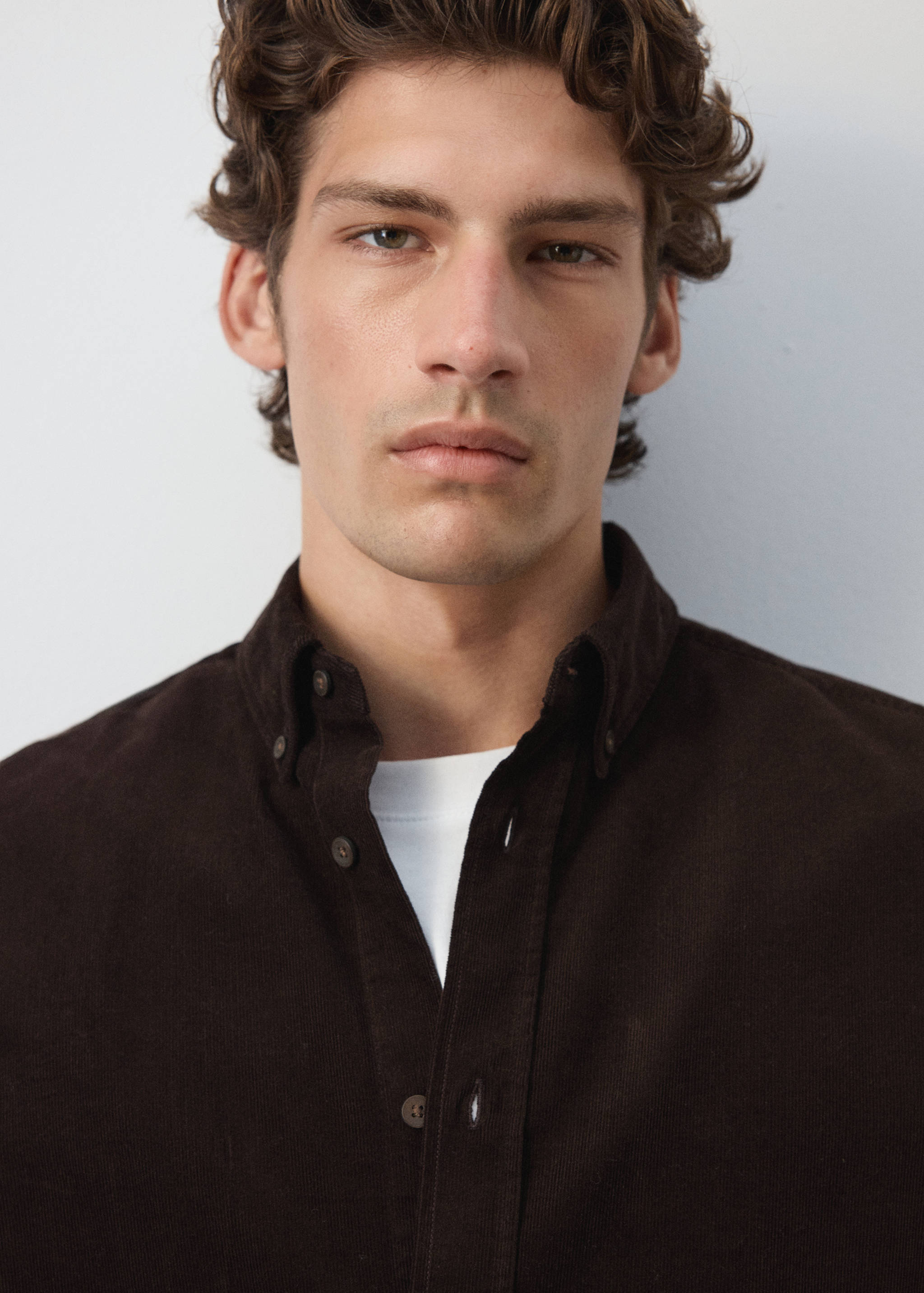 Close-up of a dark brown corduroy shirt worn with a white t-shirt.