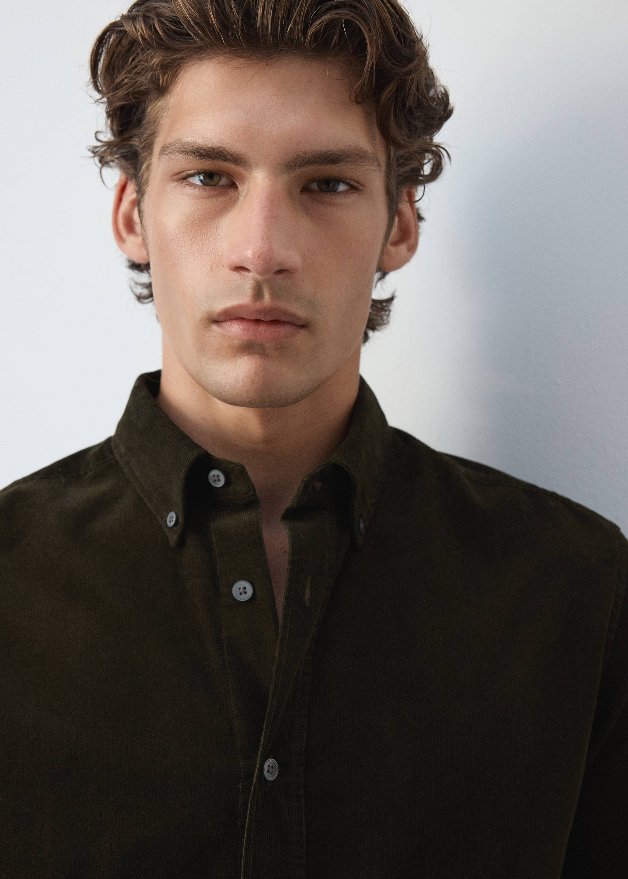 Close-up of a dark green corduroy shirt with a button-down collar.