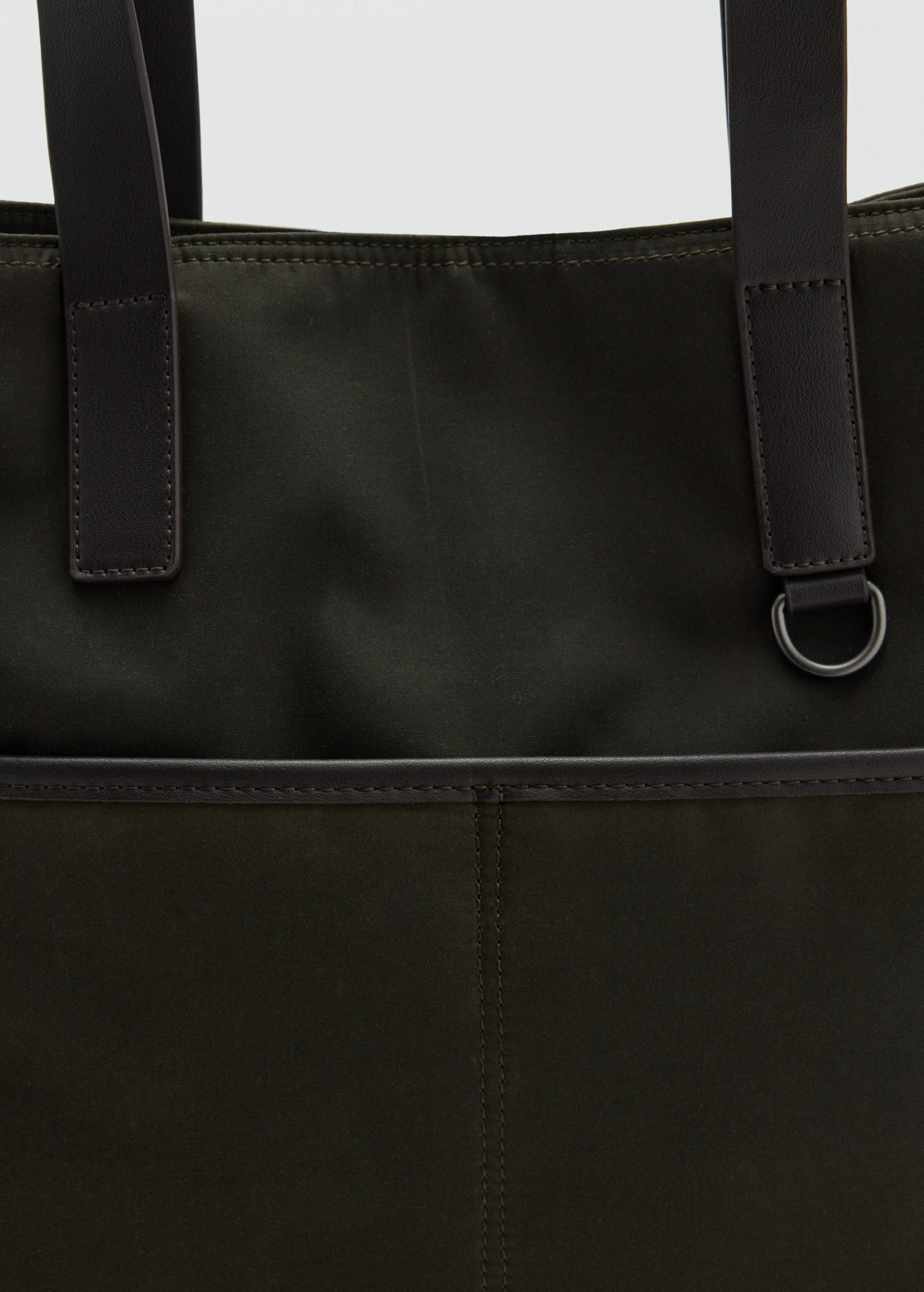 Close-up of an olive green tote bag with dark brown faux-leather handles and front pocket detail.