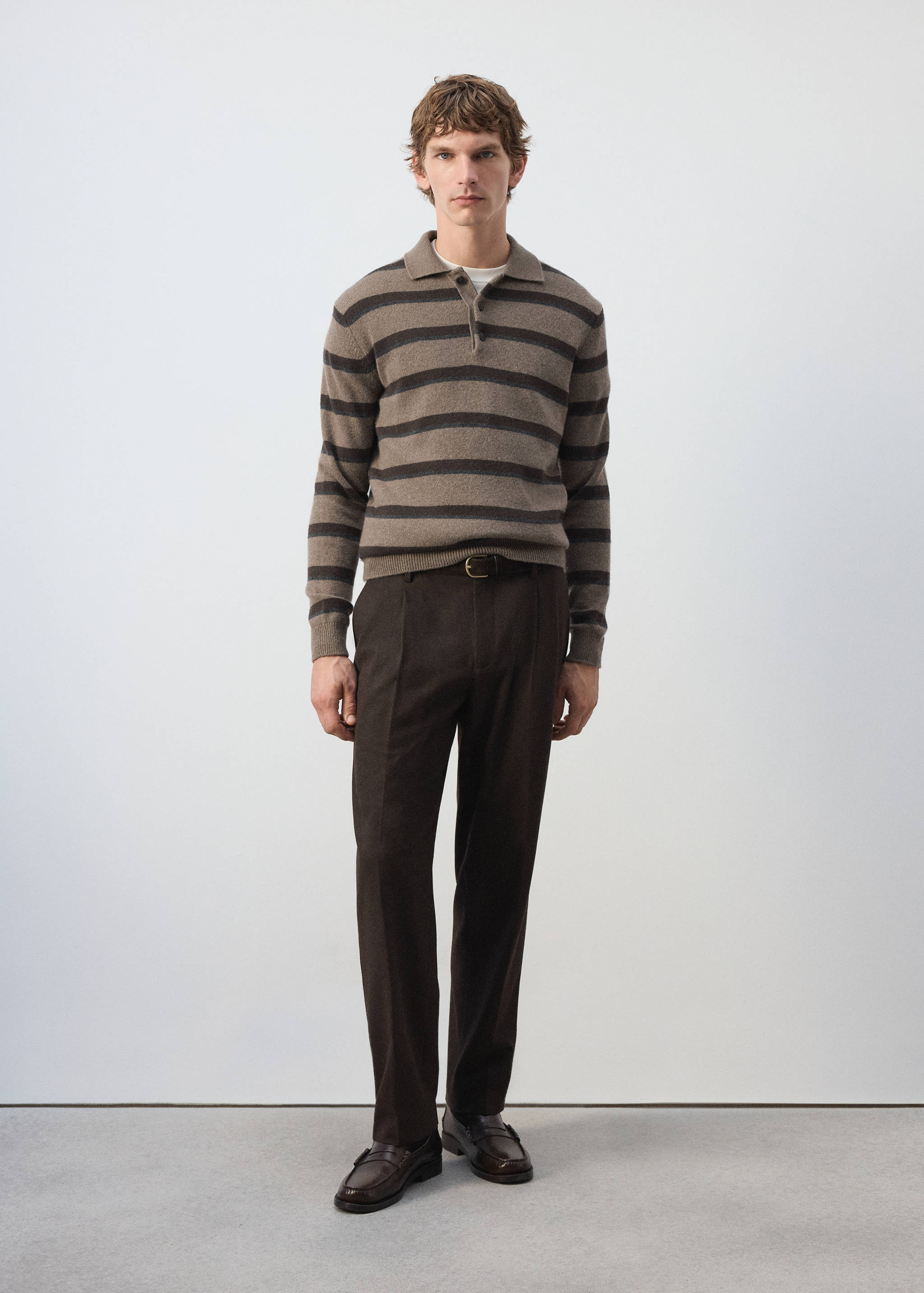 Taupe and brown striped knit polo shirt with a collar and button placket, worn with dark trousers.