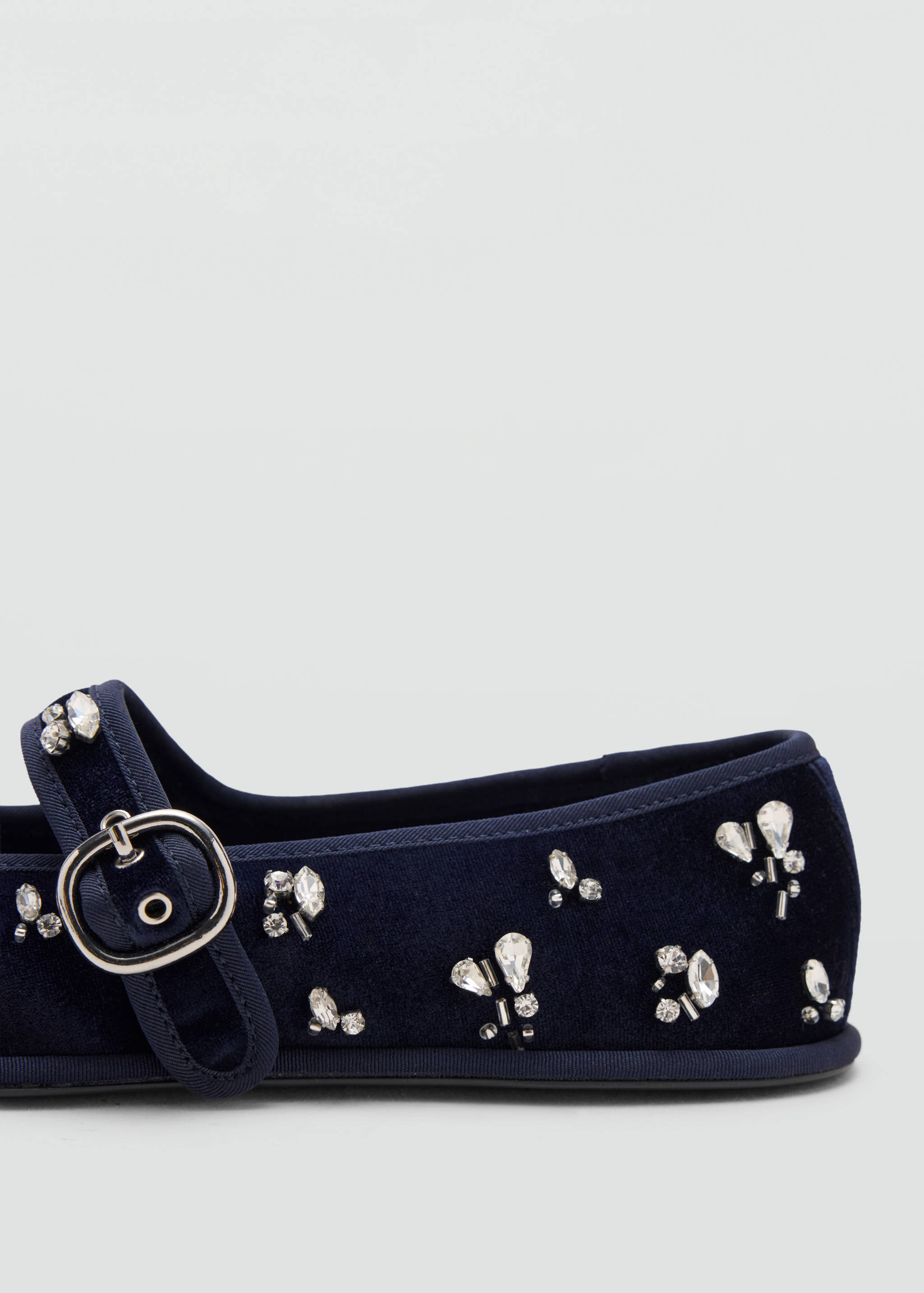 Close-up of a dark blue velvet shoe with crystal embellishments and a silver buckle.