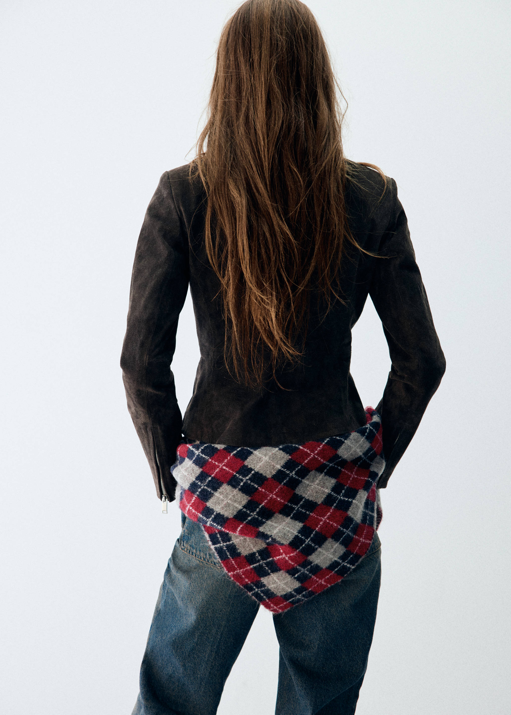 Multi-coloured checked scarf worn around the waist with a dark jacket and trousers.