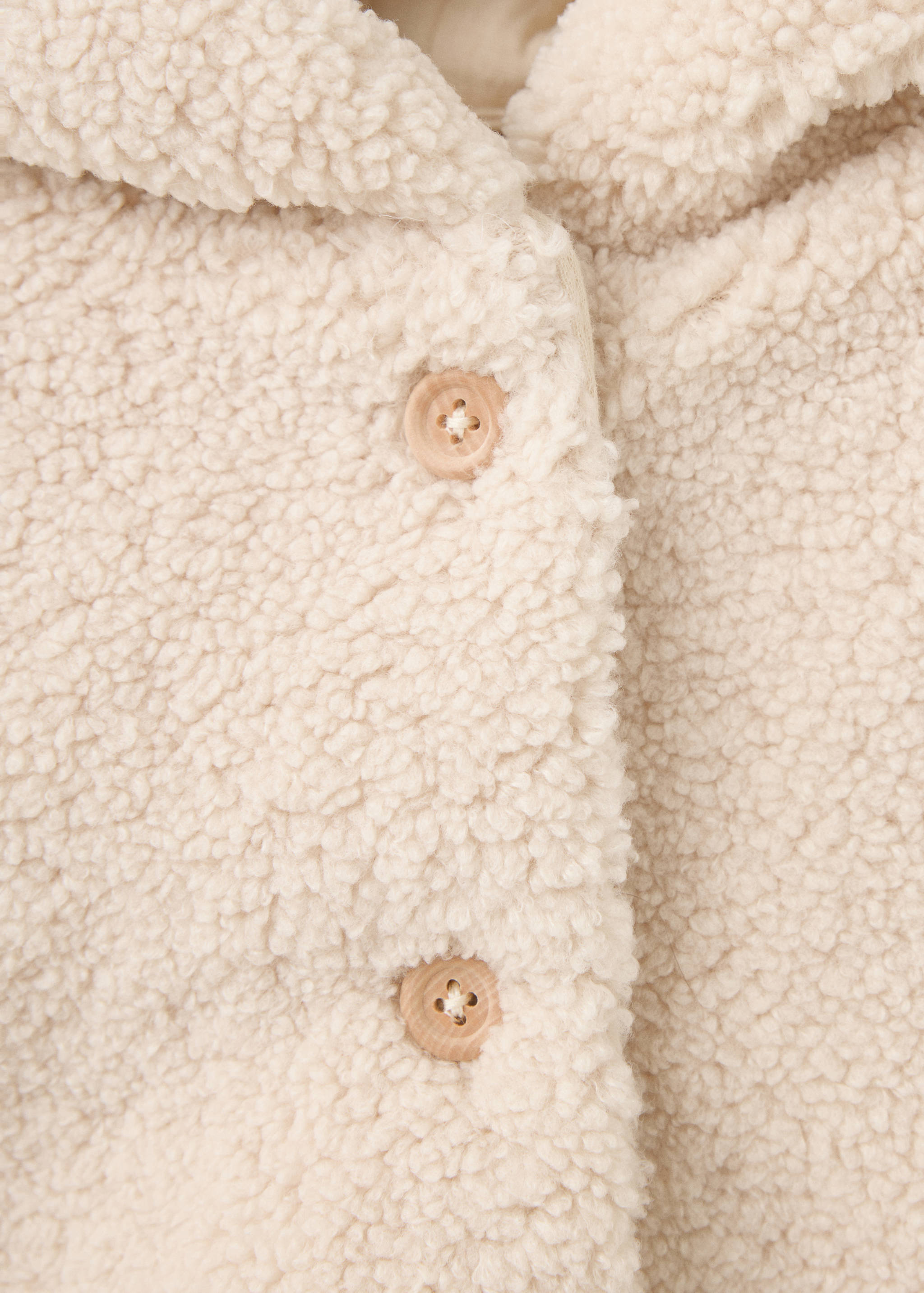 Close-up of an off-white shearling coat with wooden buttons.
