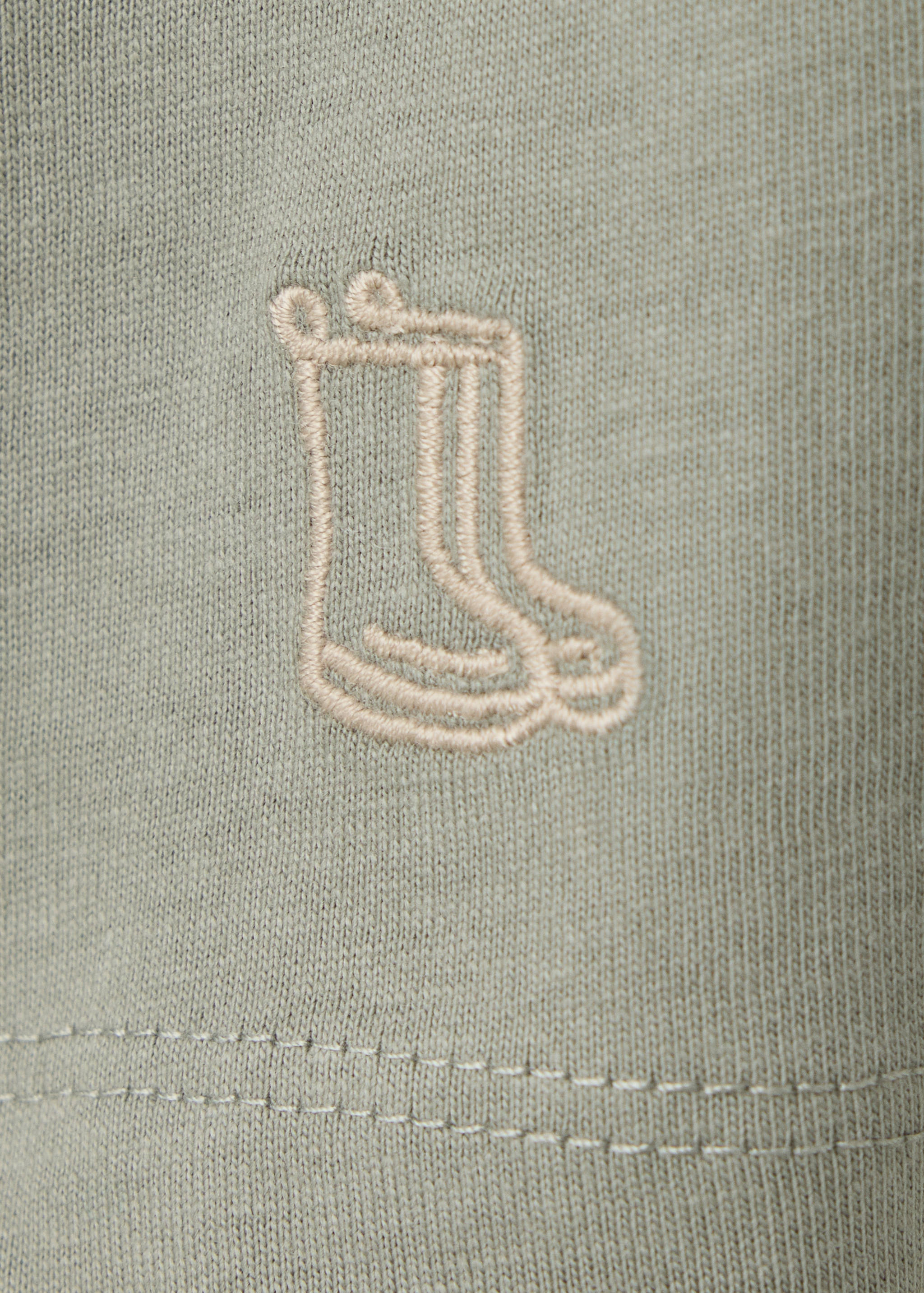 Sage green kids' polo fabric detail showing a rain boot embroidery.