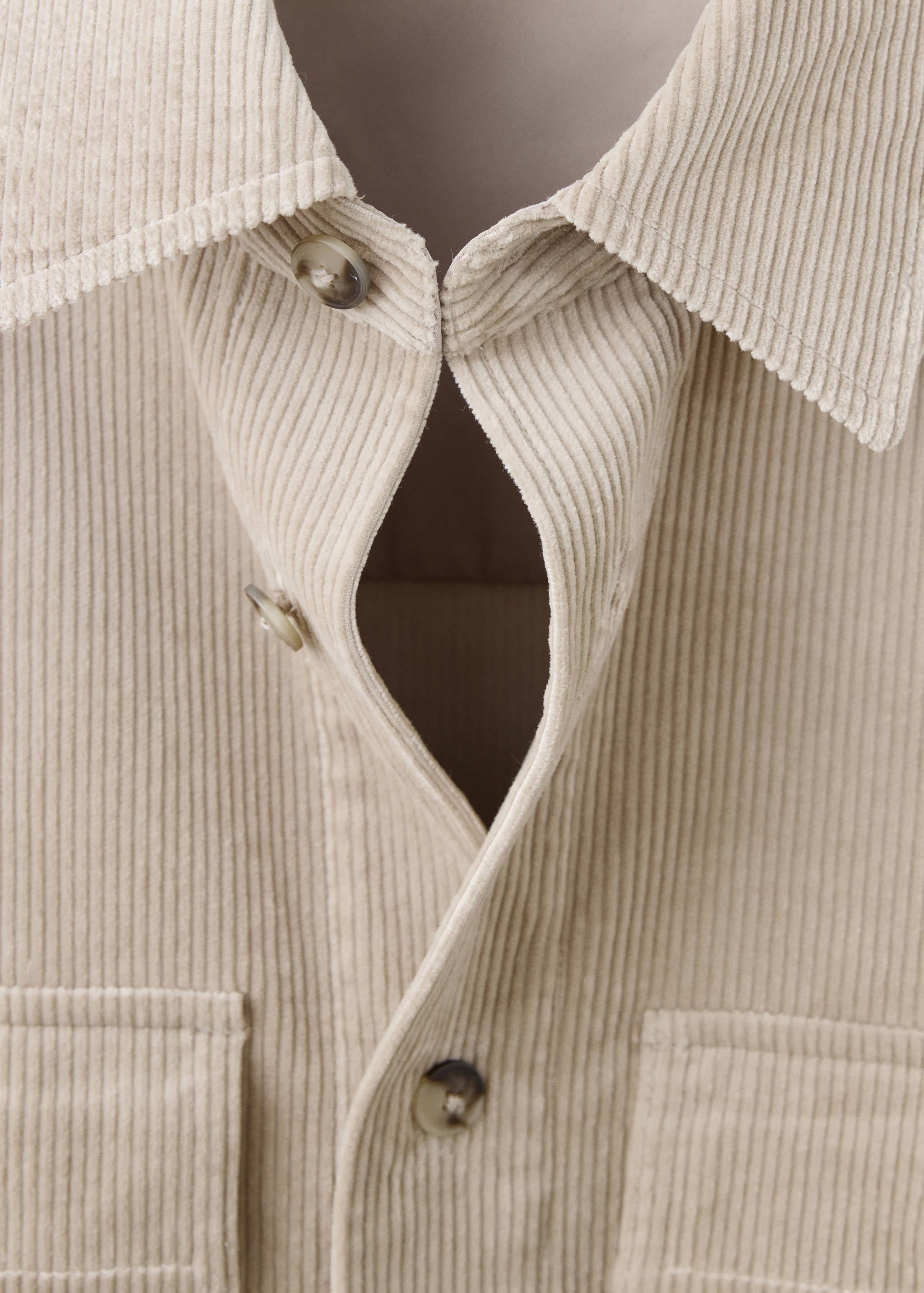 Close-up of a beige corduroy overshirt collar and button placket.