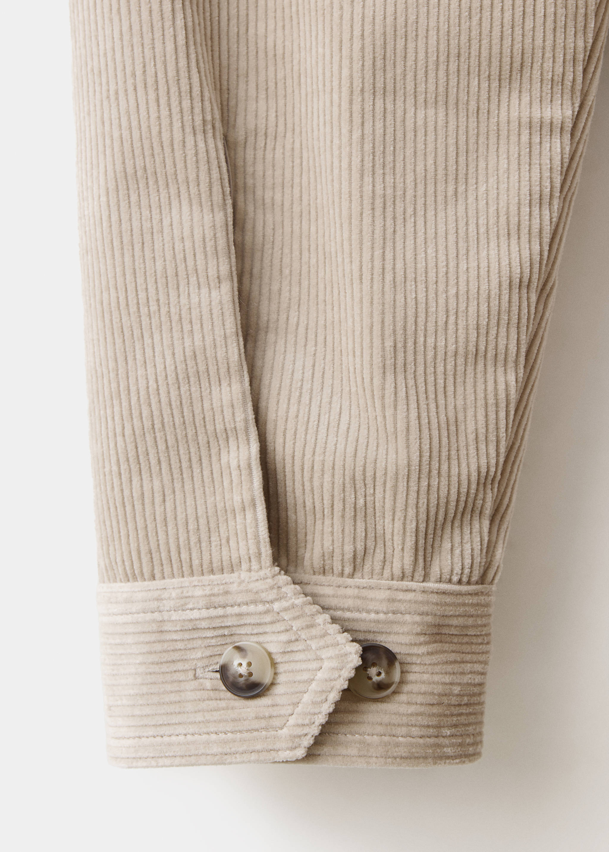 Close-up of a light beige corduroy overshirt sleeve and buttoned cuff.