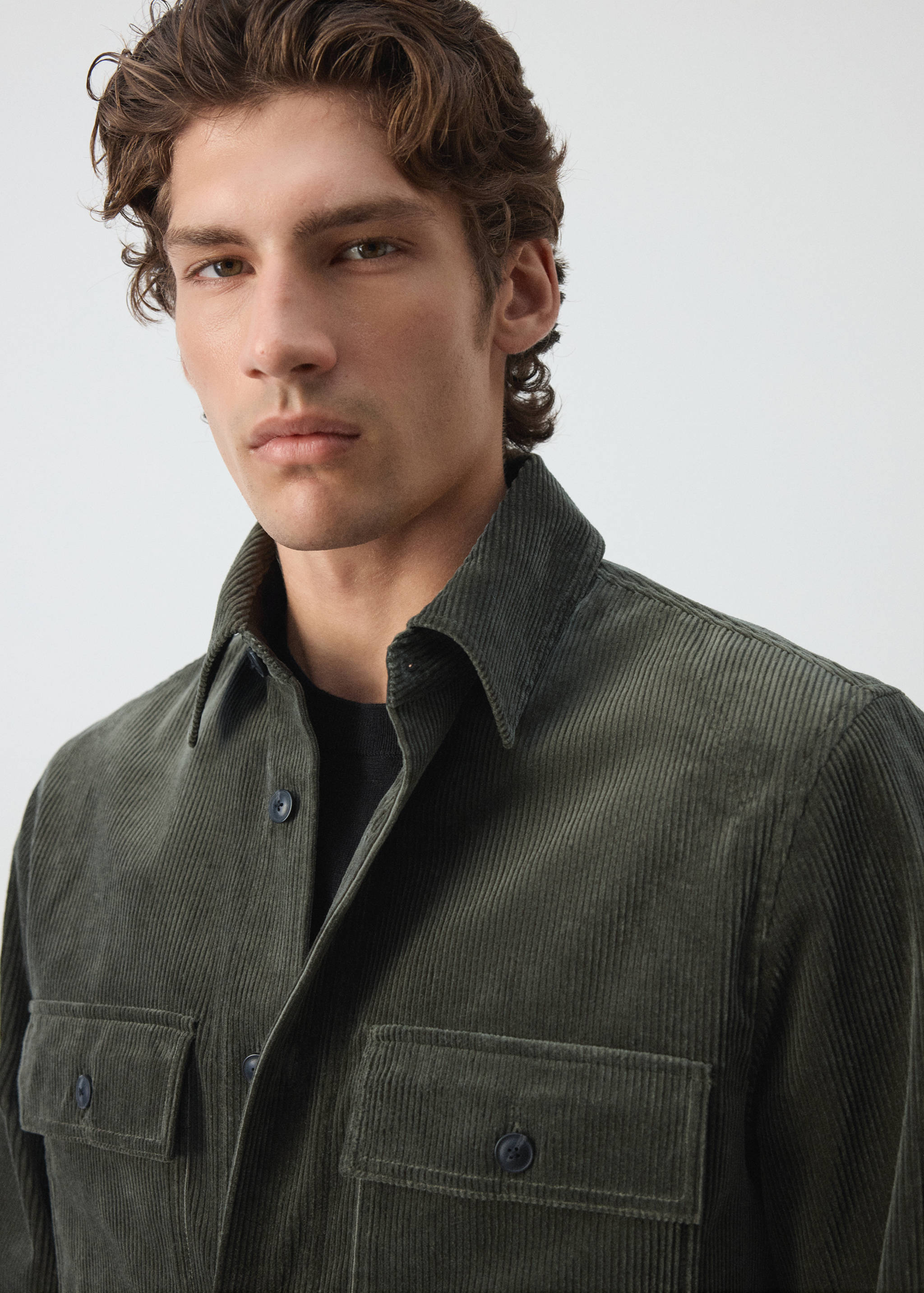 Dark green corduroy overshirt with chest pockets in a close-up model view.