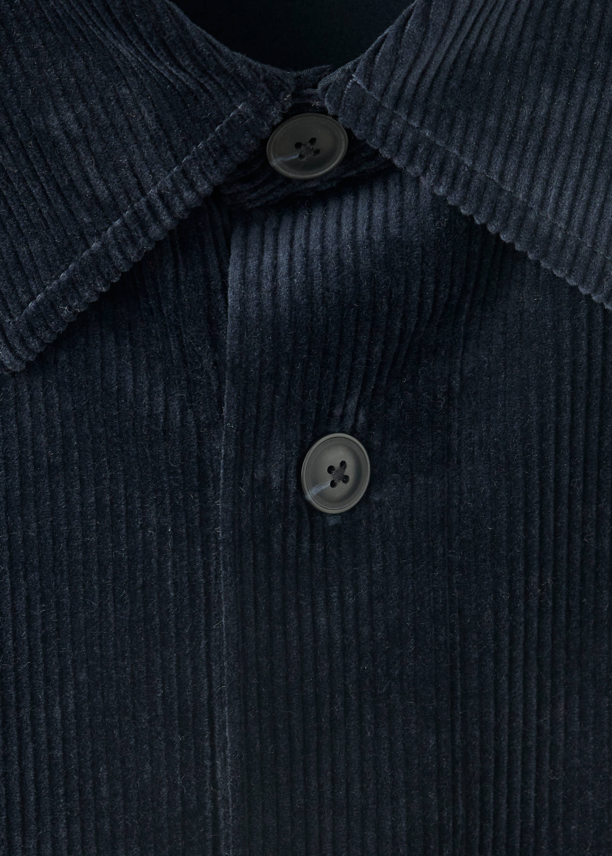 Close-up of a dark navy blue corduroy overshirt collar and buttons.