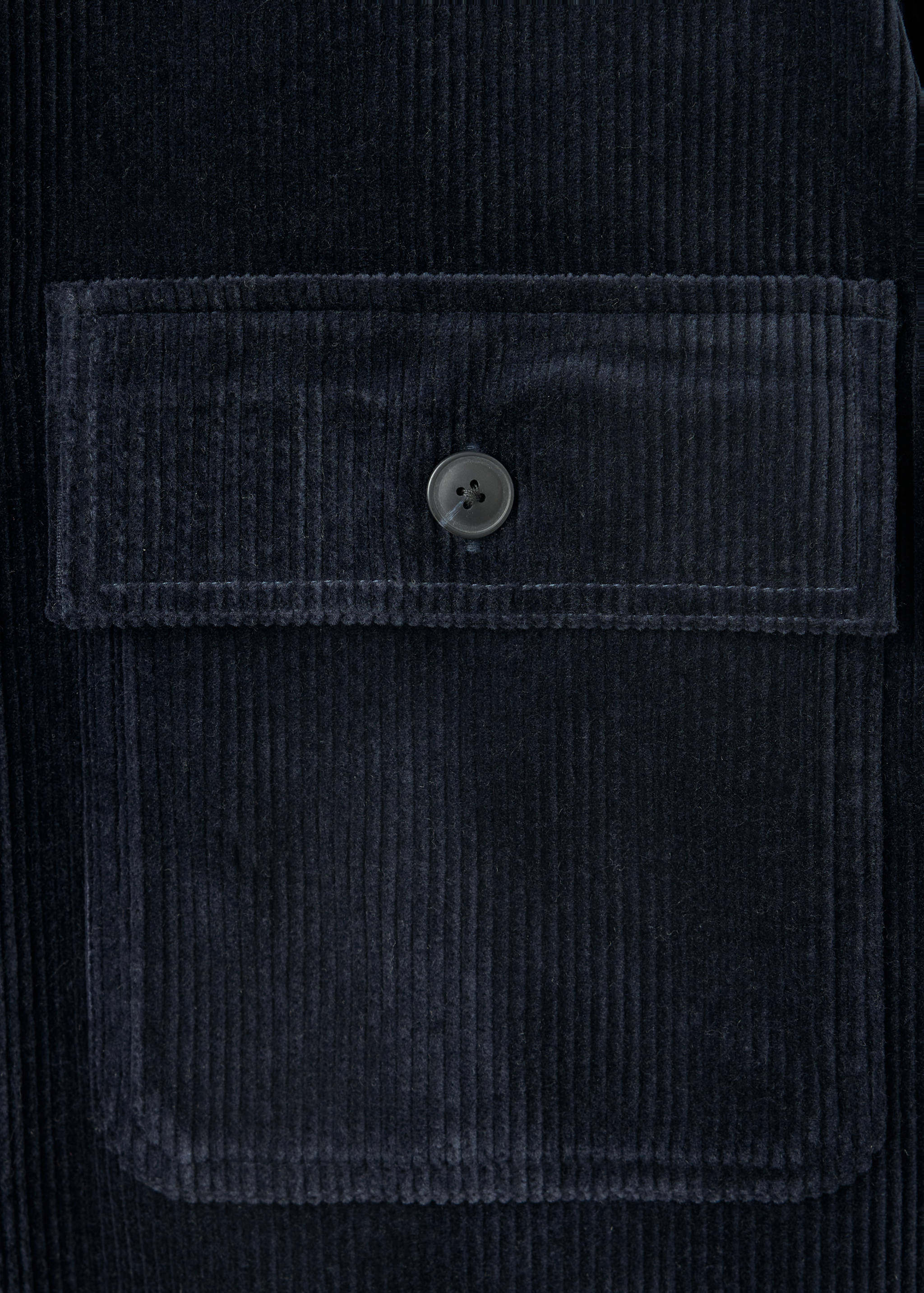 Navy blue corduroy fabric and chest pocket detail of an overshirt