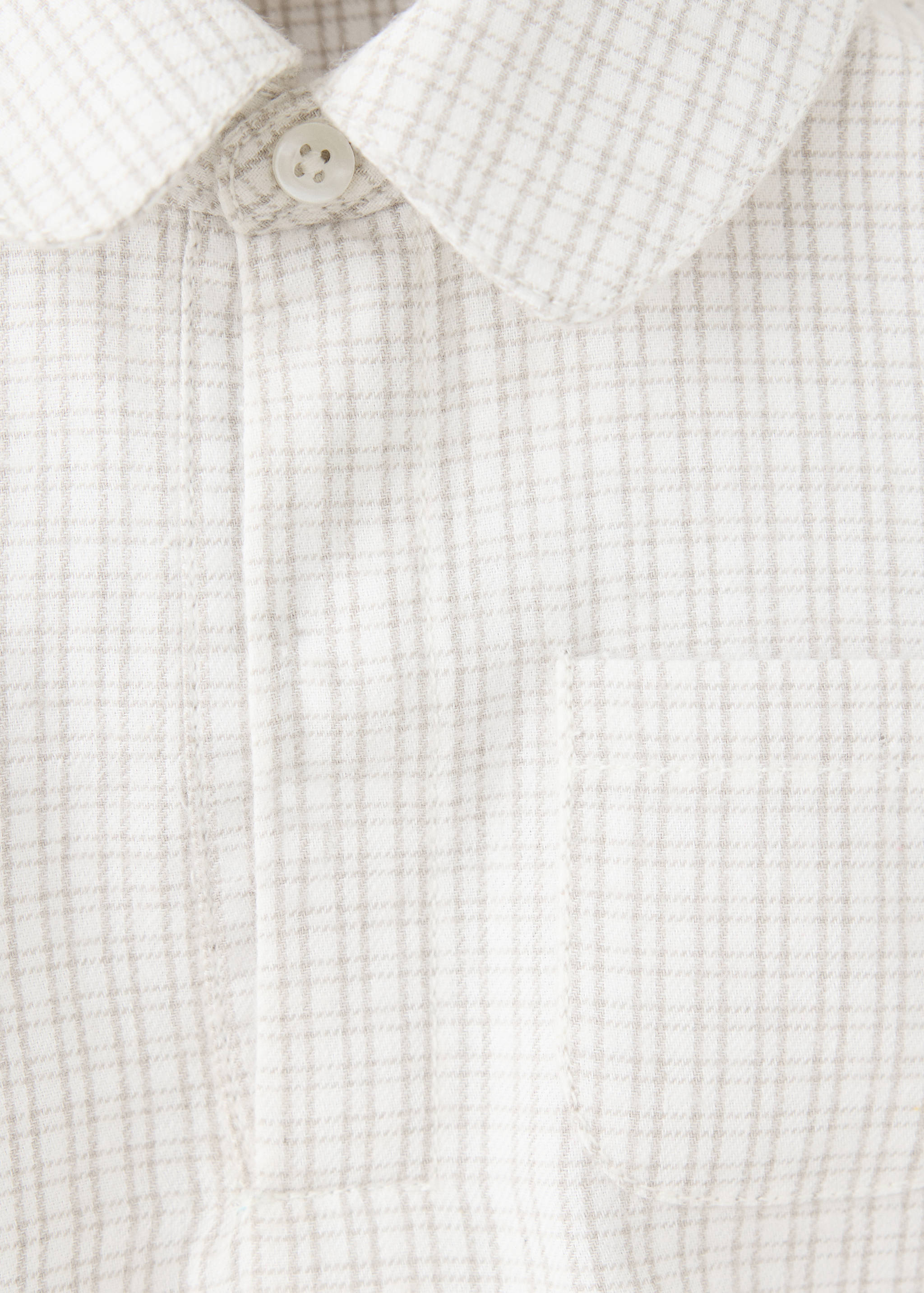 Beige and white checked kids' shirt detail with a collar and chest pocket.