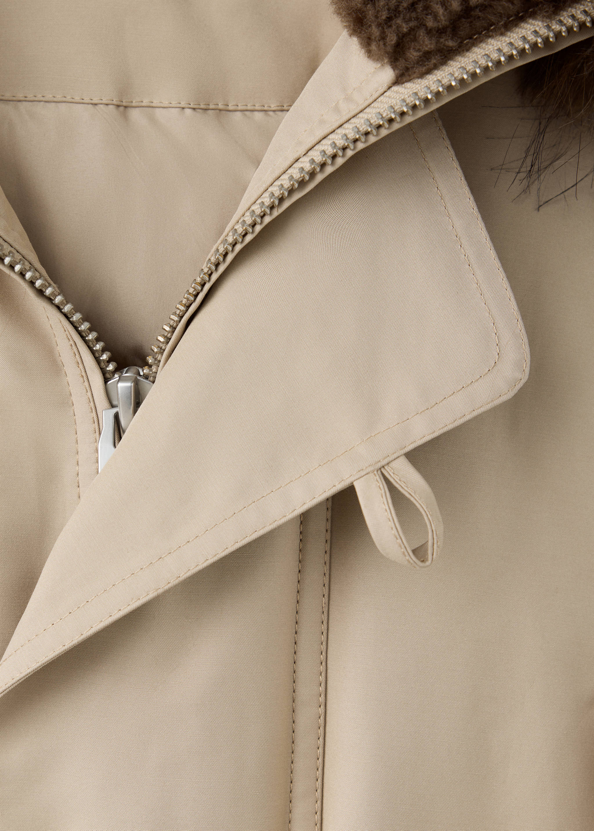 Close-up of beige jacket featuring a lapel collar, front zipper, and brown faux-fur lining.